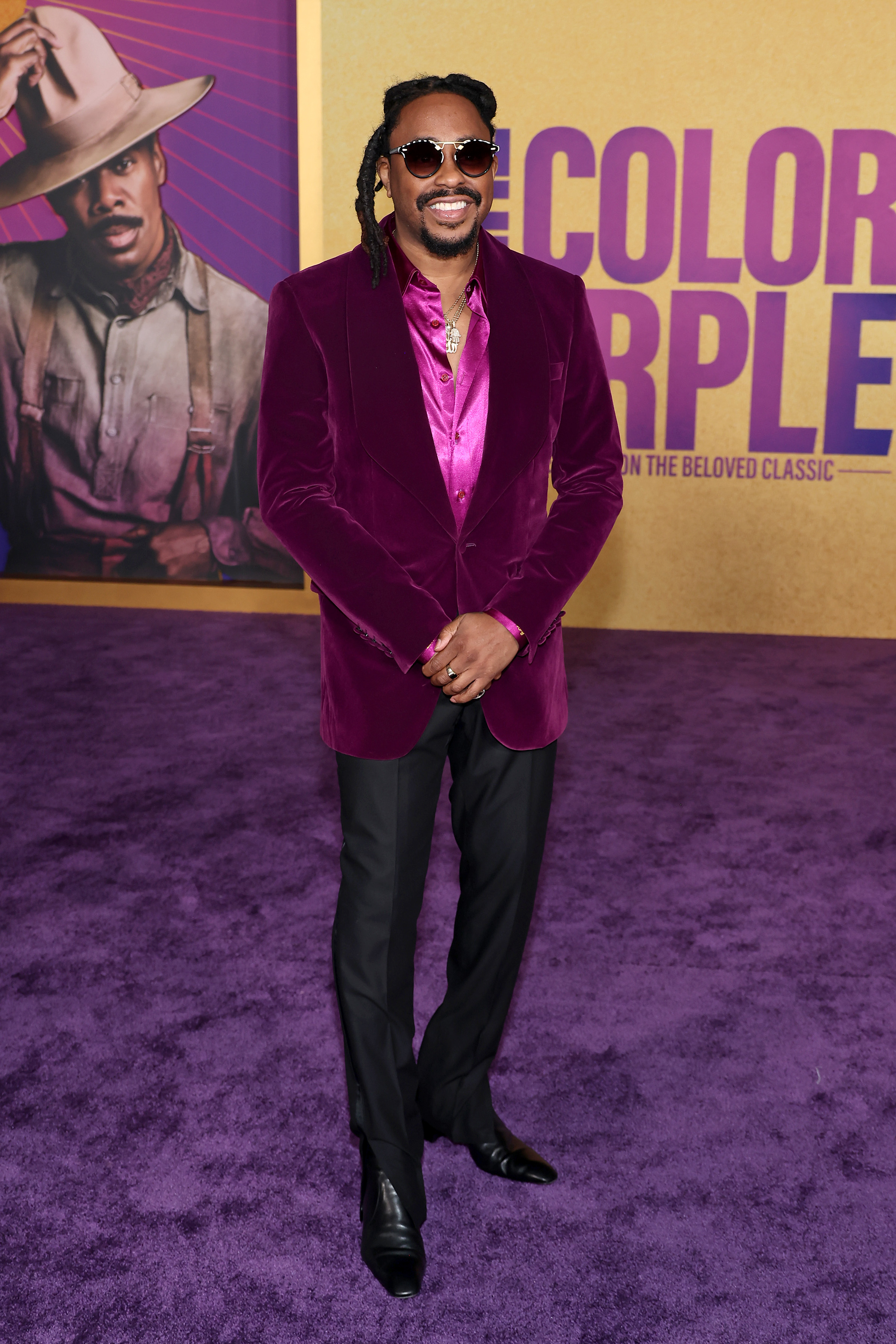 Raheem  in a purple velvet suit jacket, purple shirt, and black pants