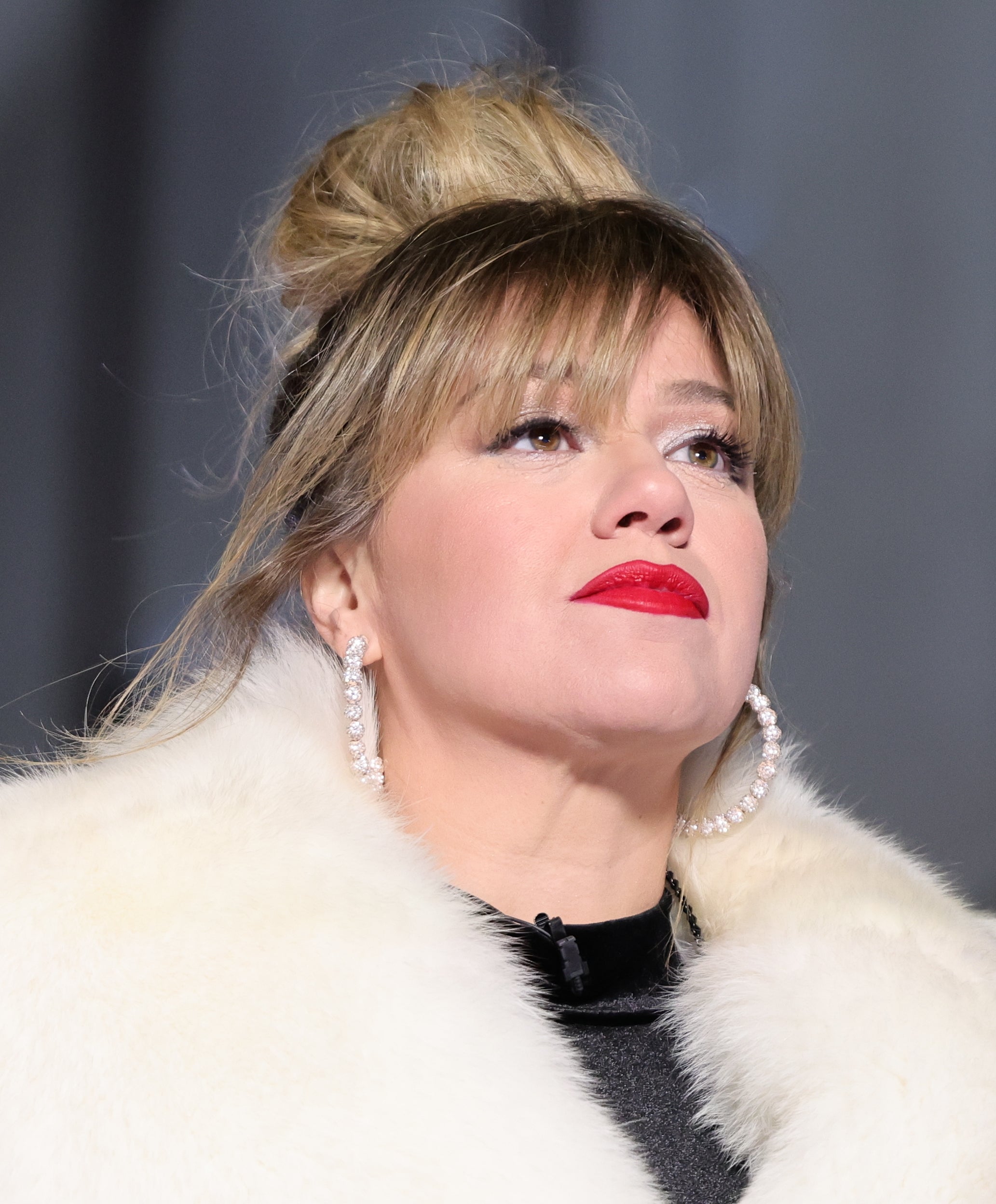 Close-up of Kelly in large hoop earrings and furry outfit