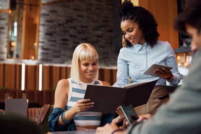 a waiter helping someone with the menu