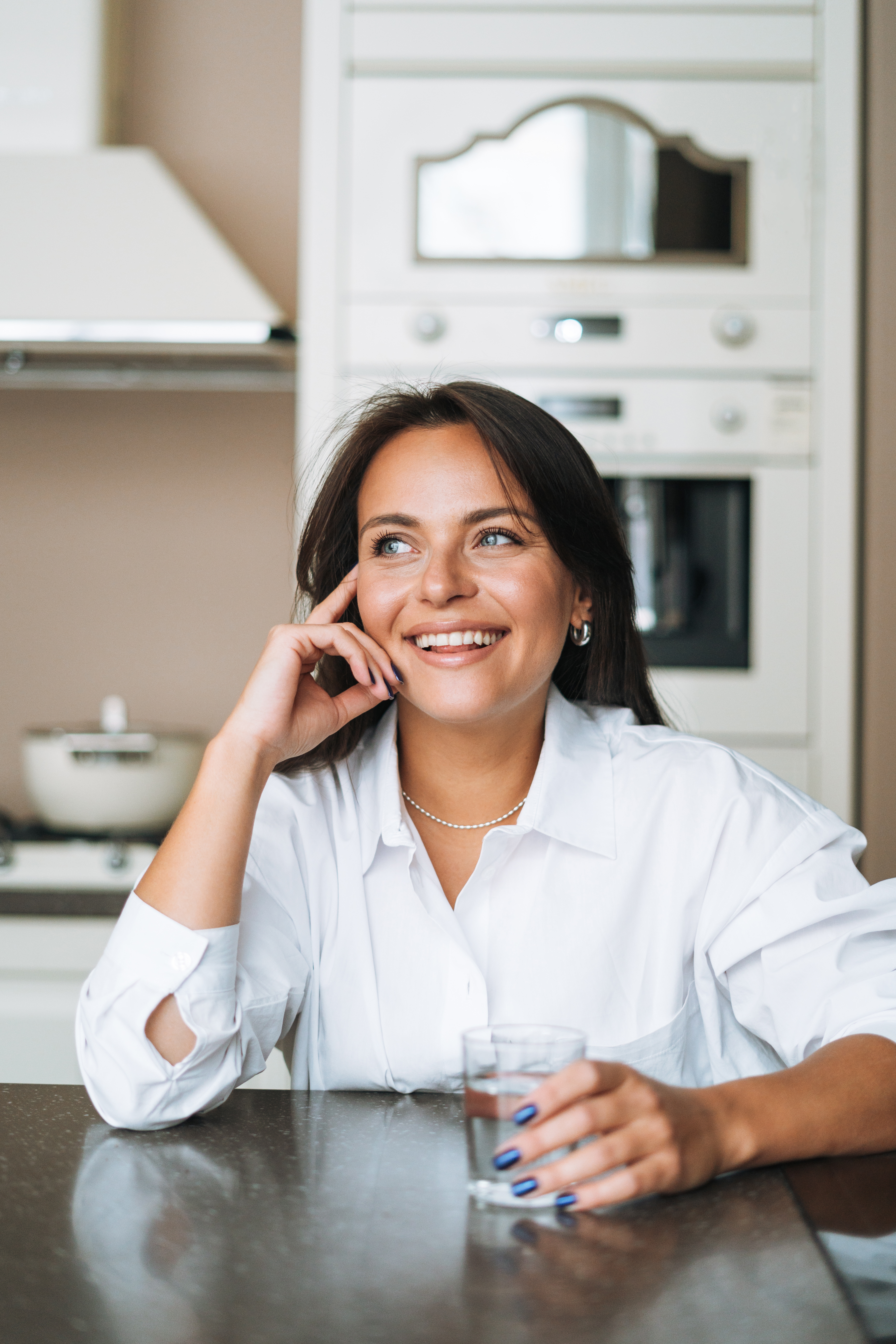 Close-up of a woman sitting at a kitchen table and smiling