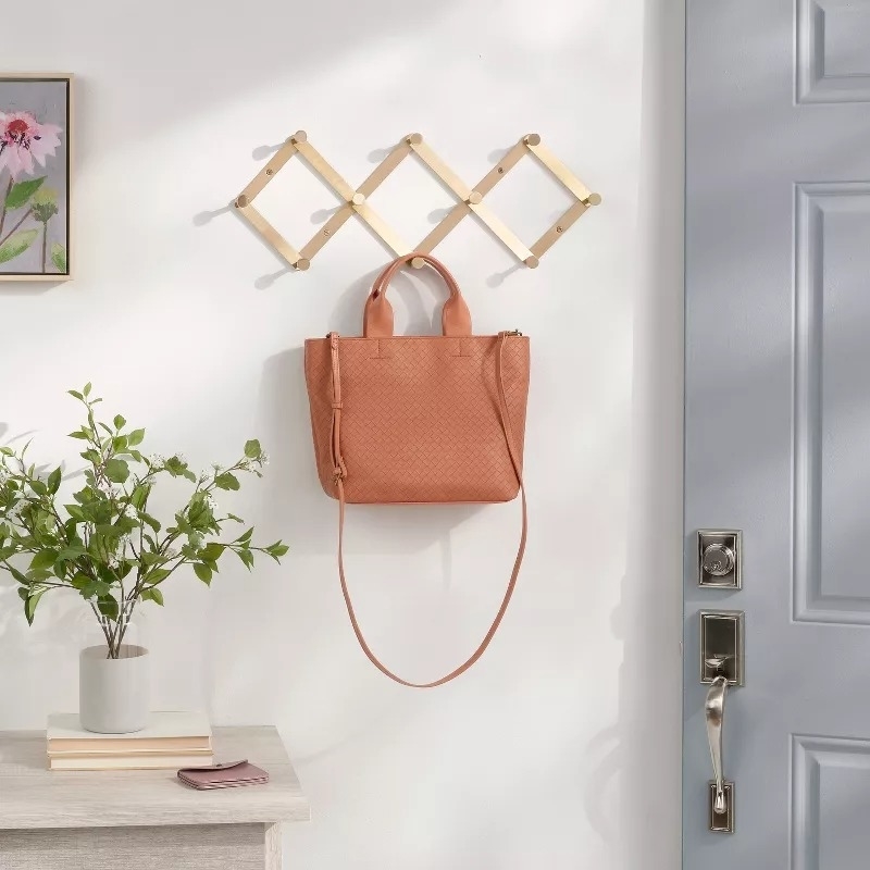 Leather tote bag hanging on a wooden rack by the door, ideal for versatile style