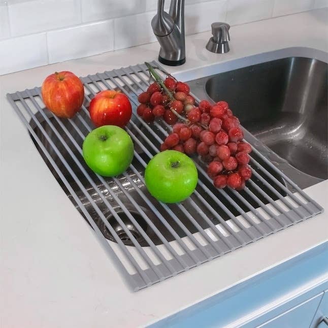 gray stainless steel dish rack with fruit over sink