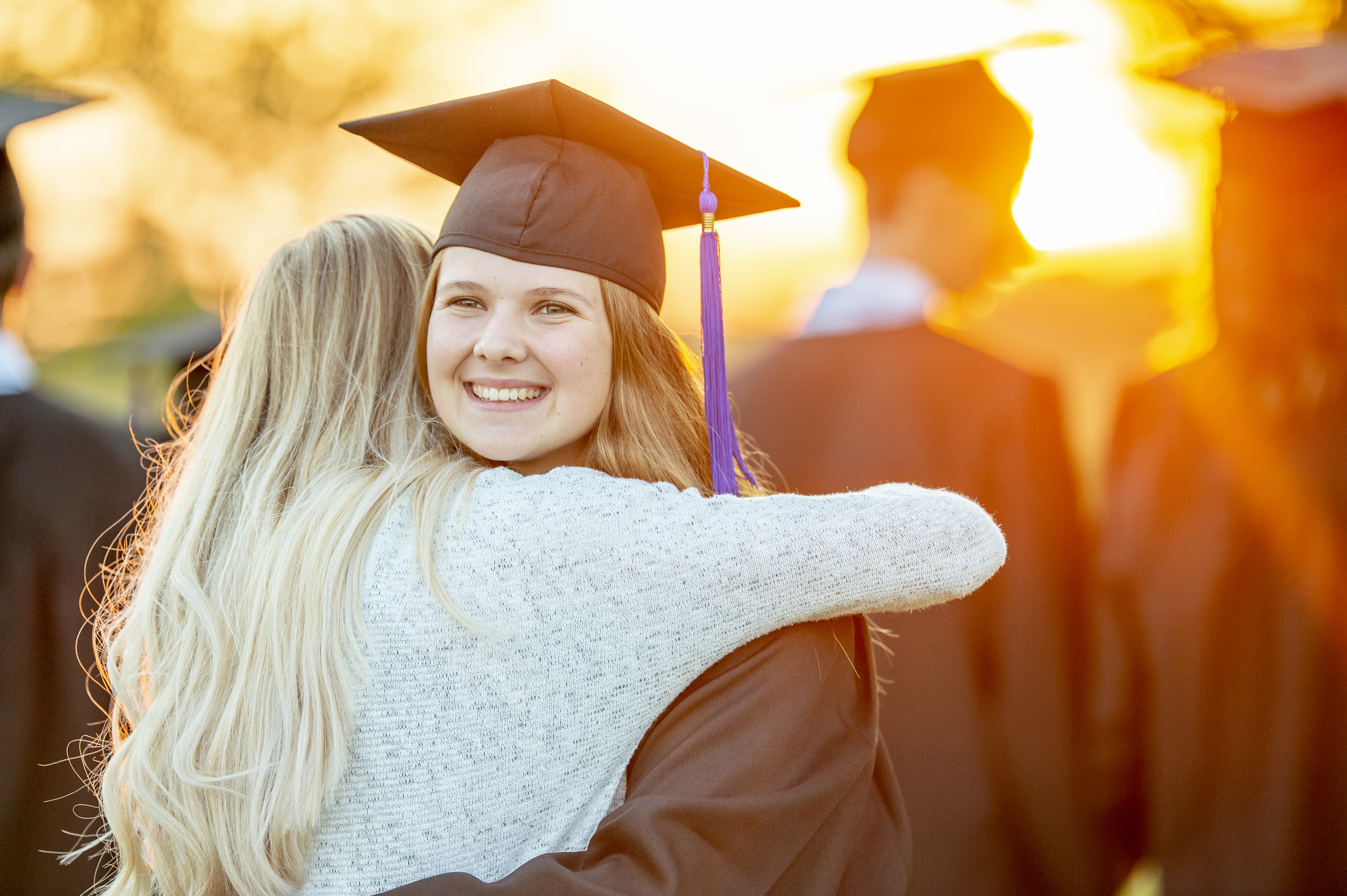 a girl in her graduation outfit hugging her friend in causal wear
