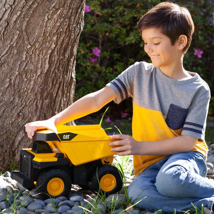 a child playing with the mini dump truck in a yard