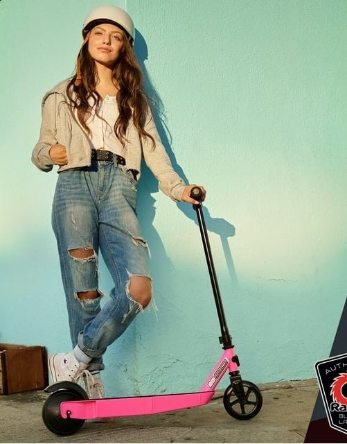 model standing next to pink Razor scooter