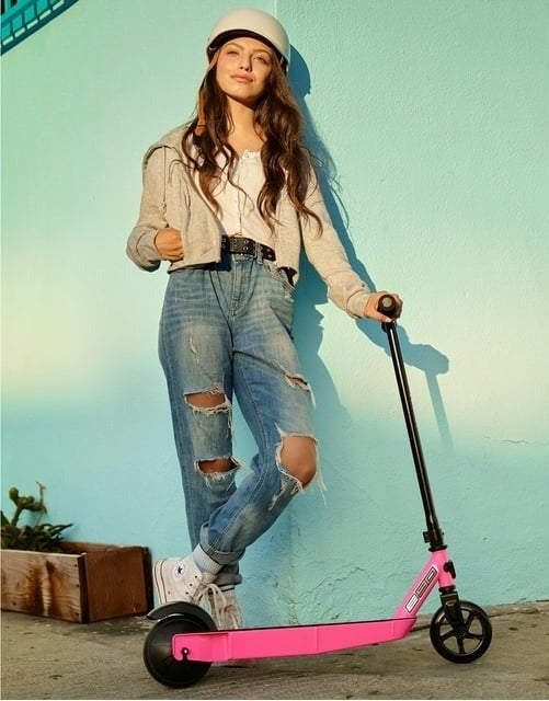 model standing next to pink Razor scooter