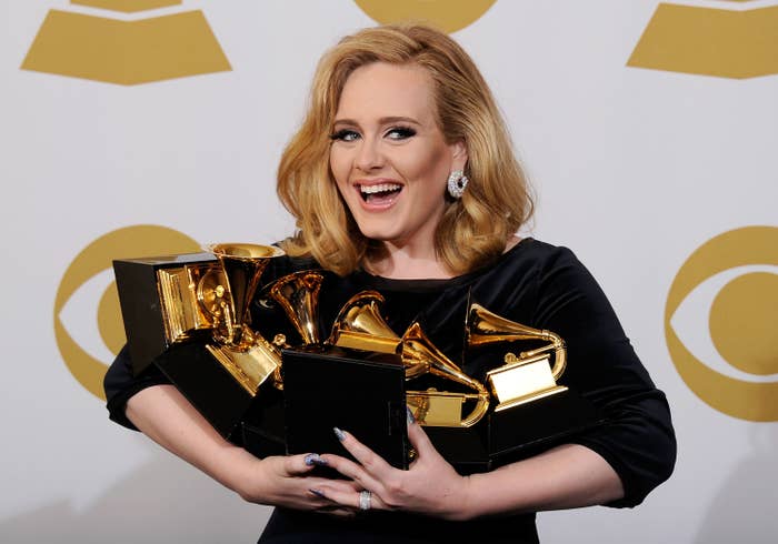 Adele smiling and holding many Grammys