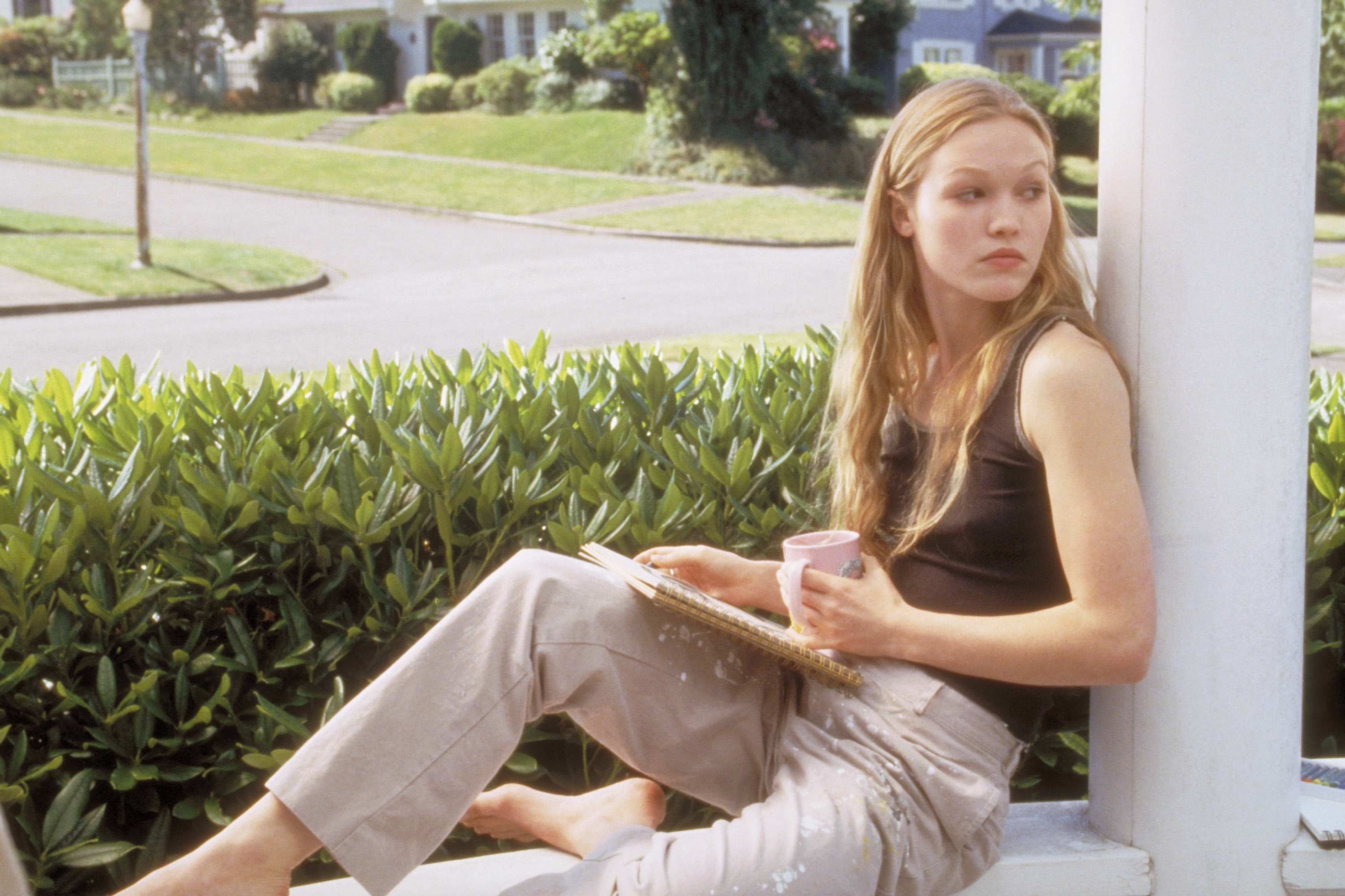 Julia in the movie resting against a beam outside with a notebook in her lap