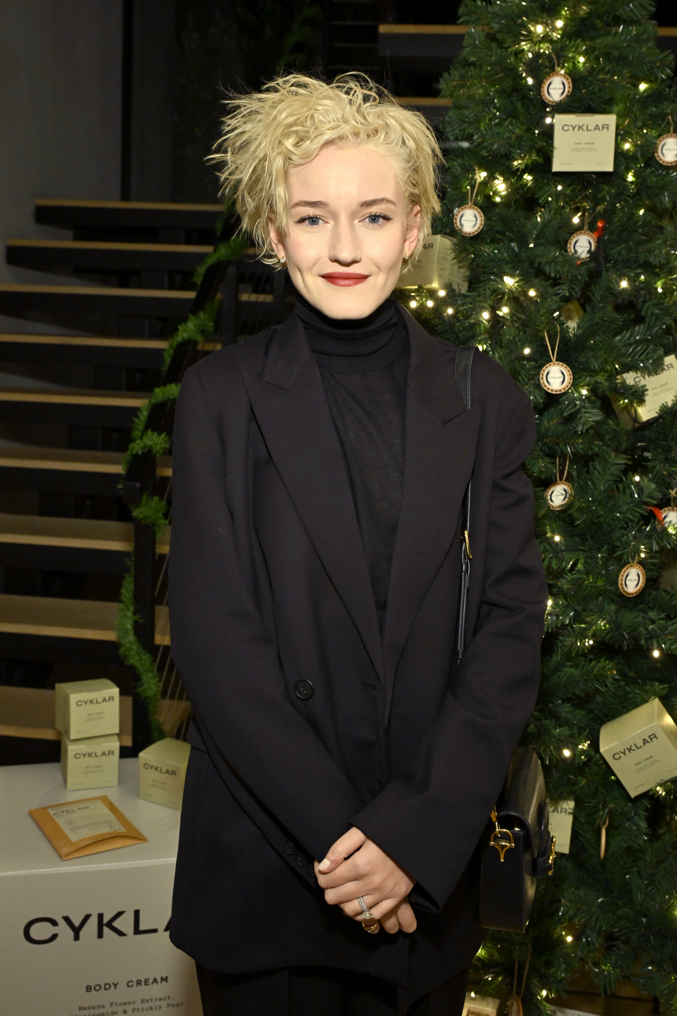 closeup of her by a christmas tree wearing a long blazer