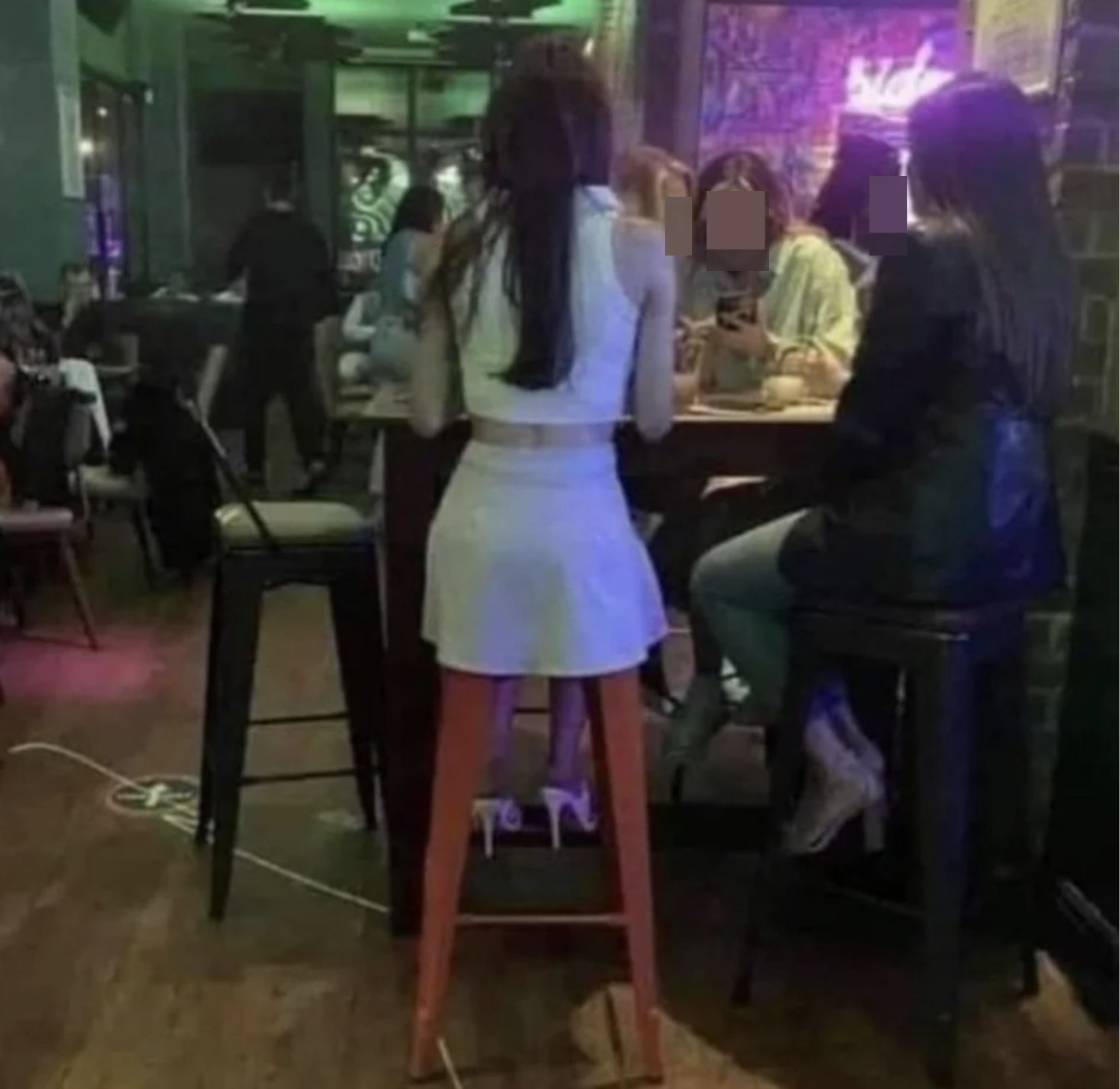 woman sitting on a bar stool with her skirt circling it so it looks like it might be her legs
