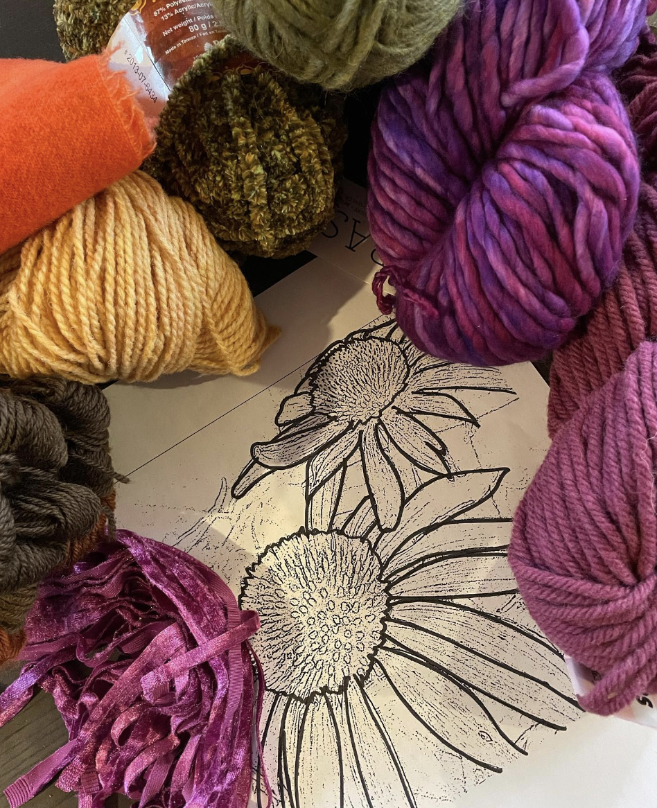 Colourful yarn surrounding a line drawing of sunflowers.
