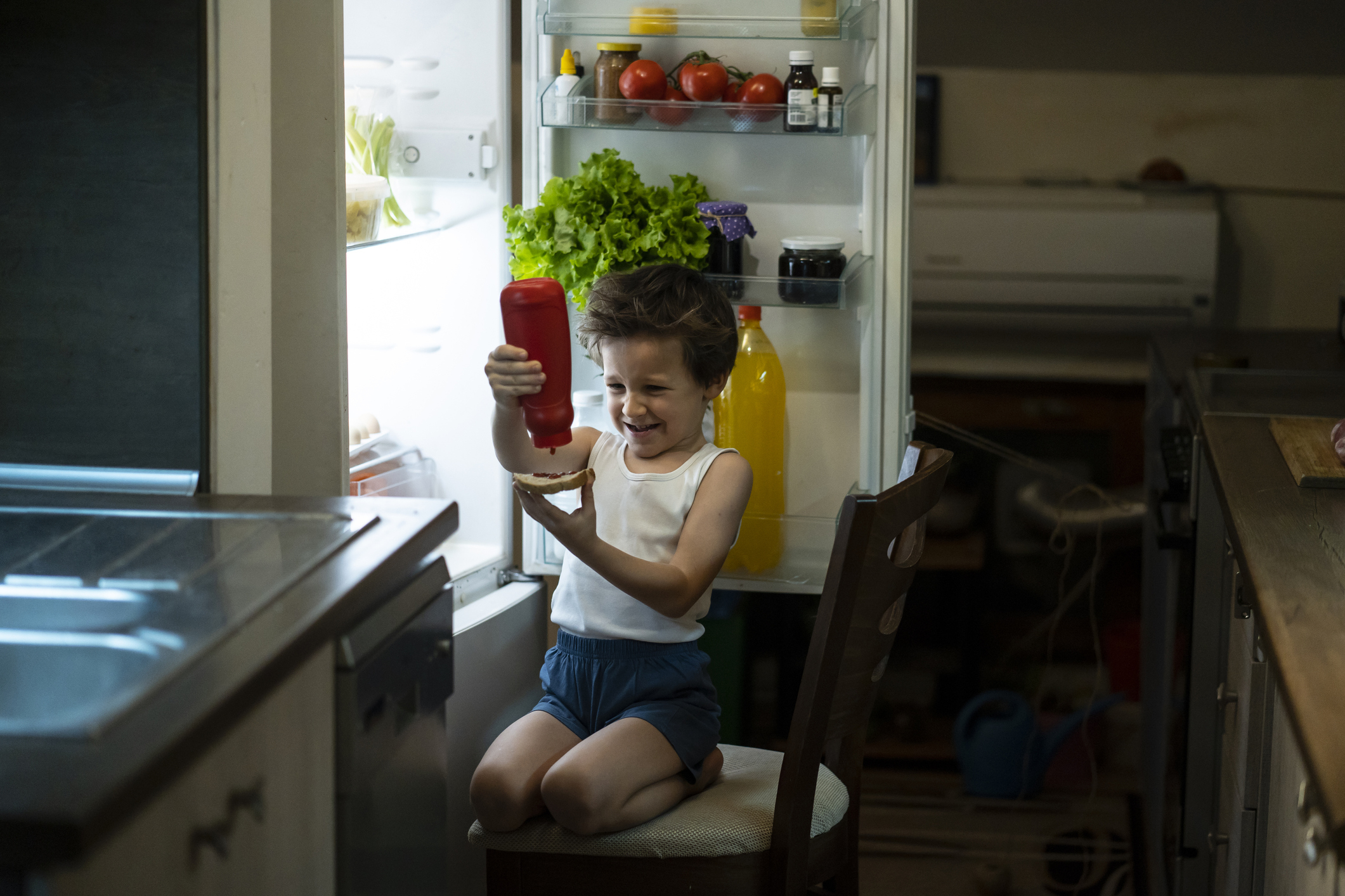 kid pouring ketchup on a piece of bread