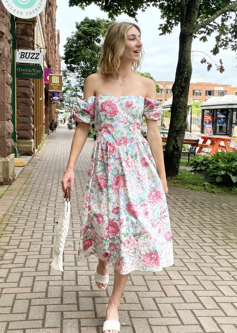 A woman walks with a beautiful floral sundress.
