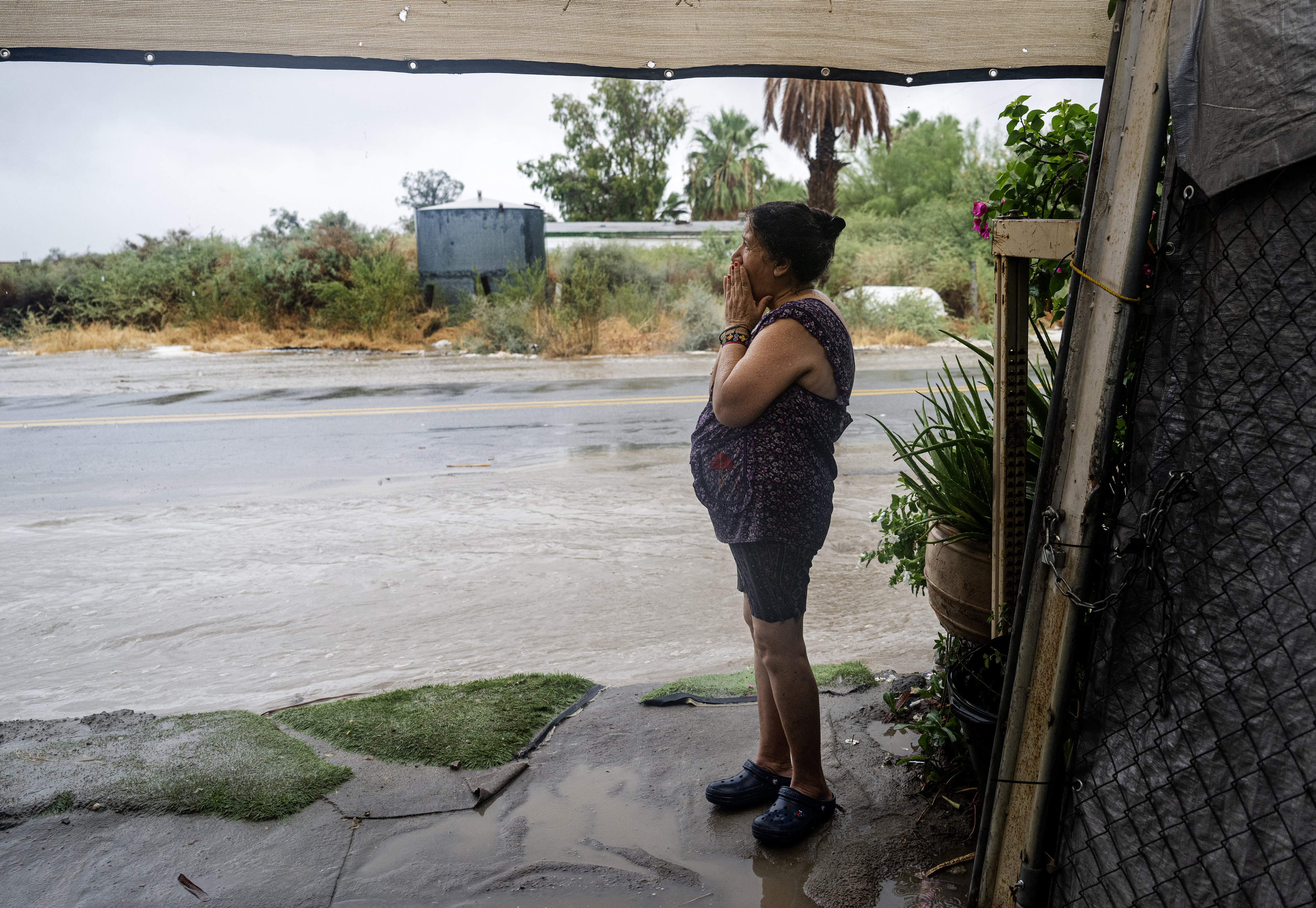 older woman watching from her home in California as water rushers down the street