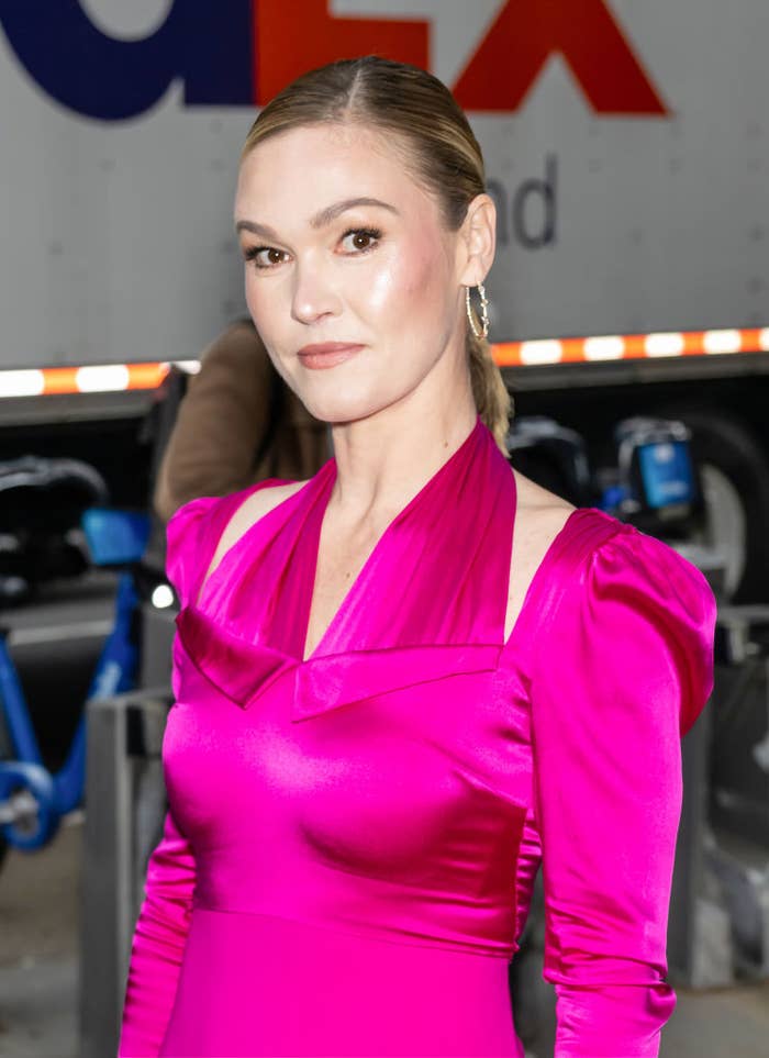 Close-up of Julia at a media event in a neon pink cutout halter-top outfit