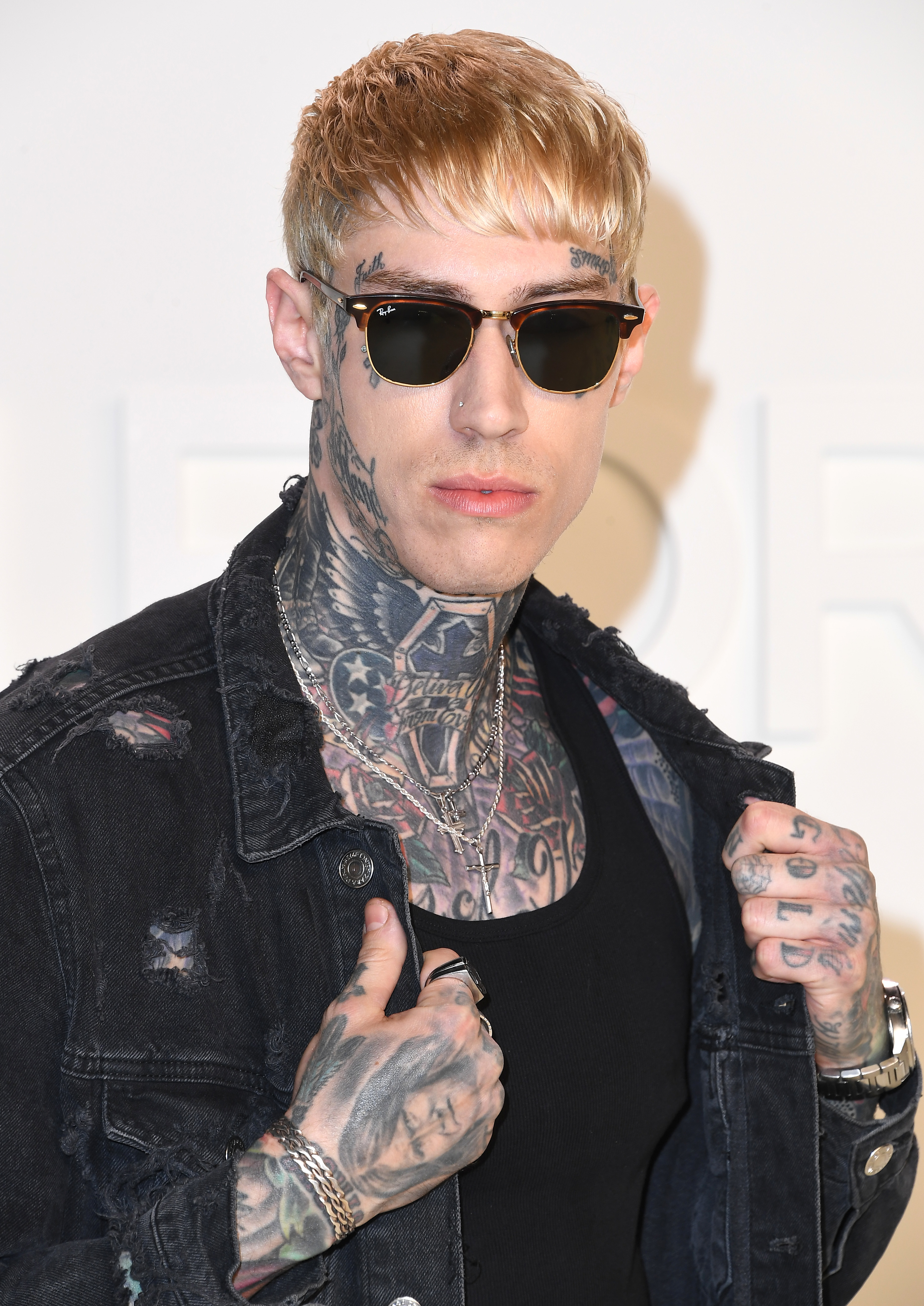 Close-up of Trace at a media event wearing sunglasses and showing many tattoos