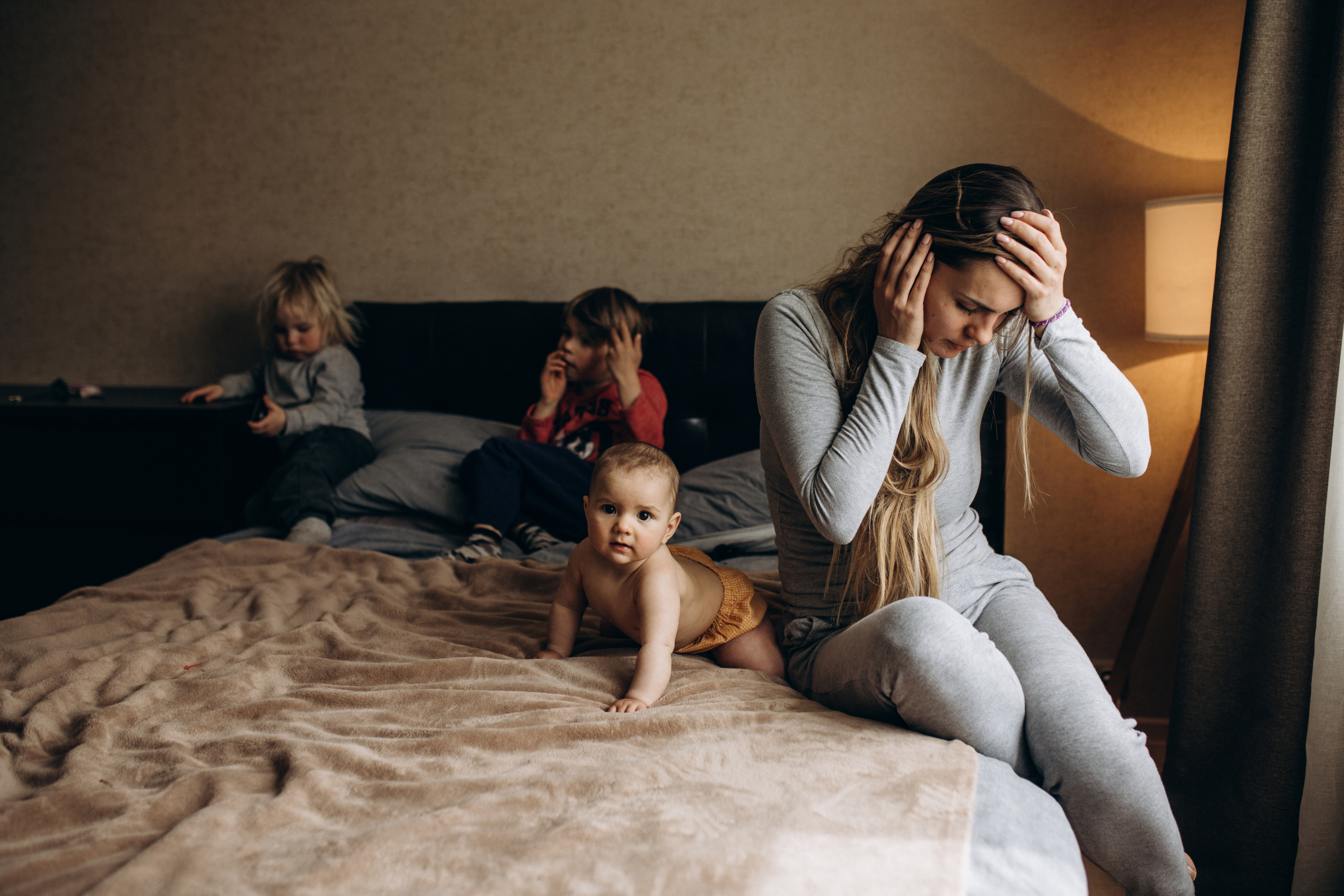 a stressed mother and her kids on a bed