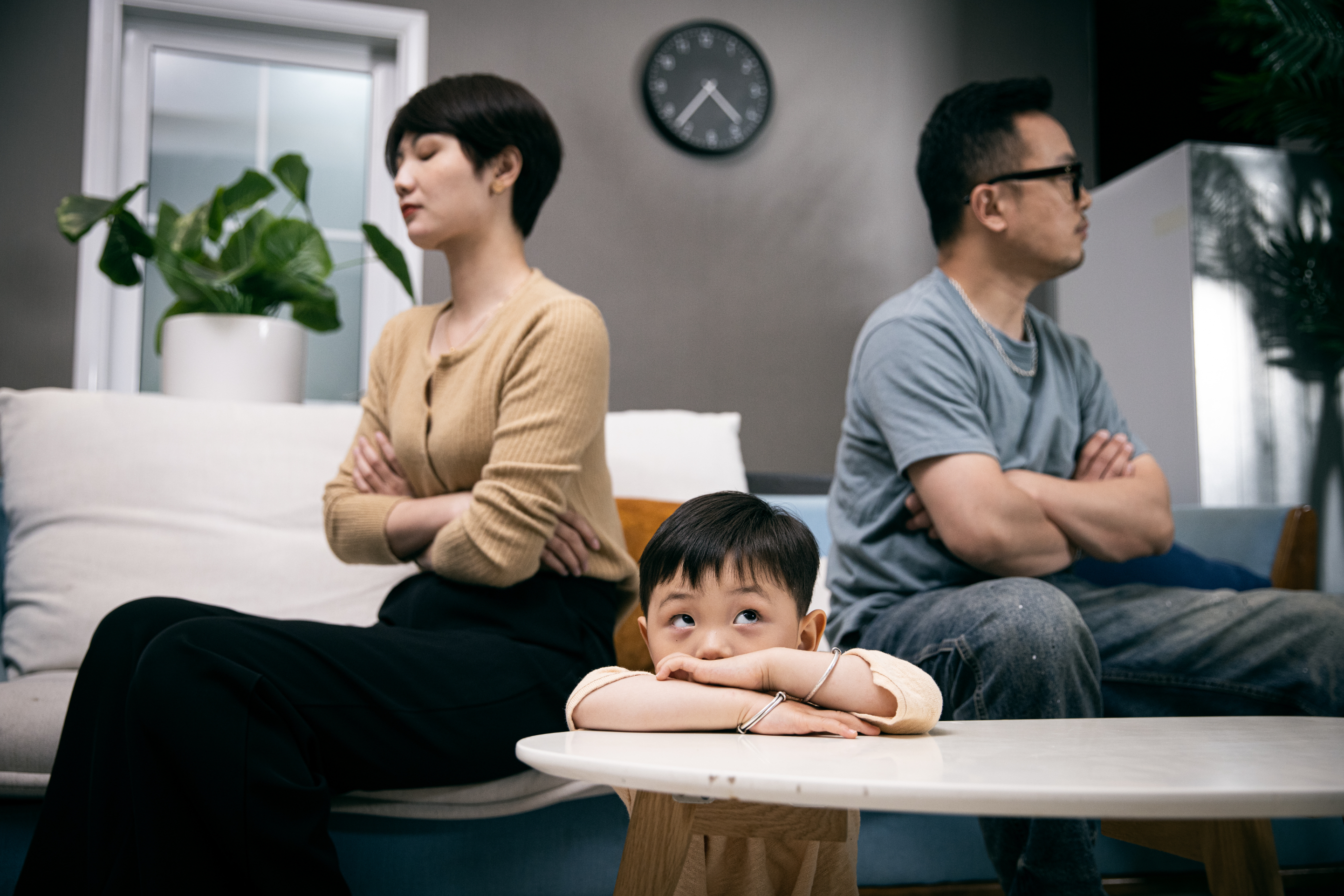 a child sitting in front of his parents who are avoiding each other