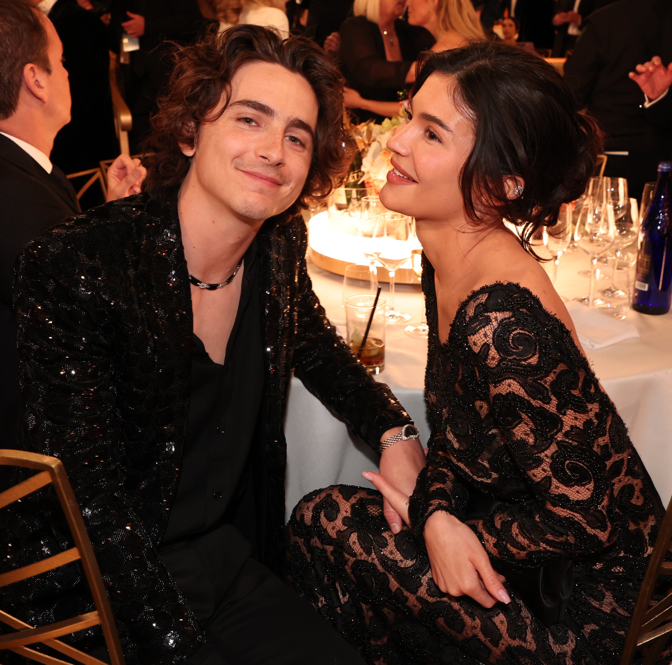 kylie and timmy holding hands and sitting at their table at the golden globes