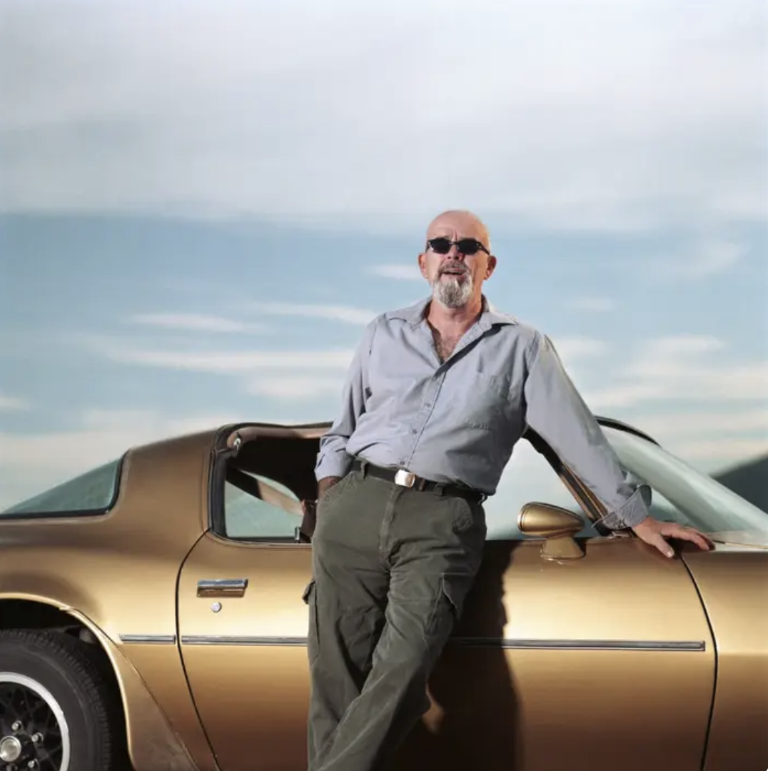 An older gentleman standing next to a sports car