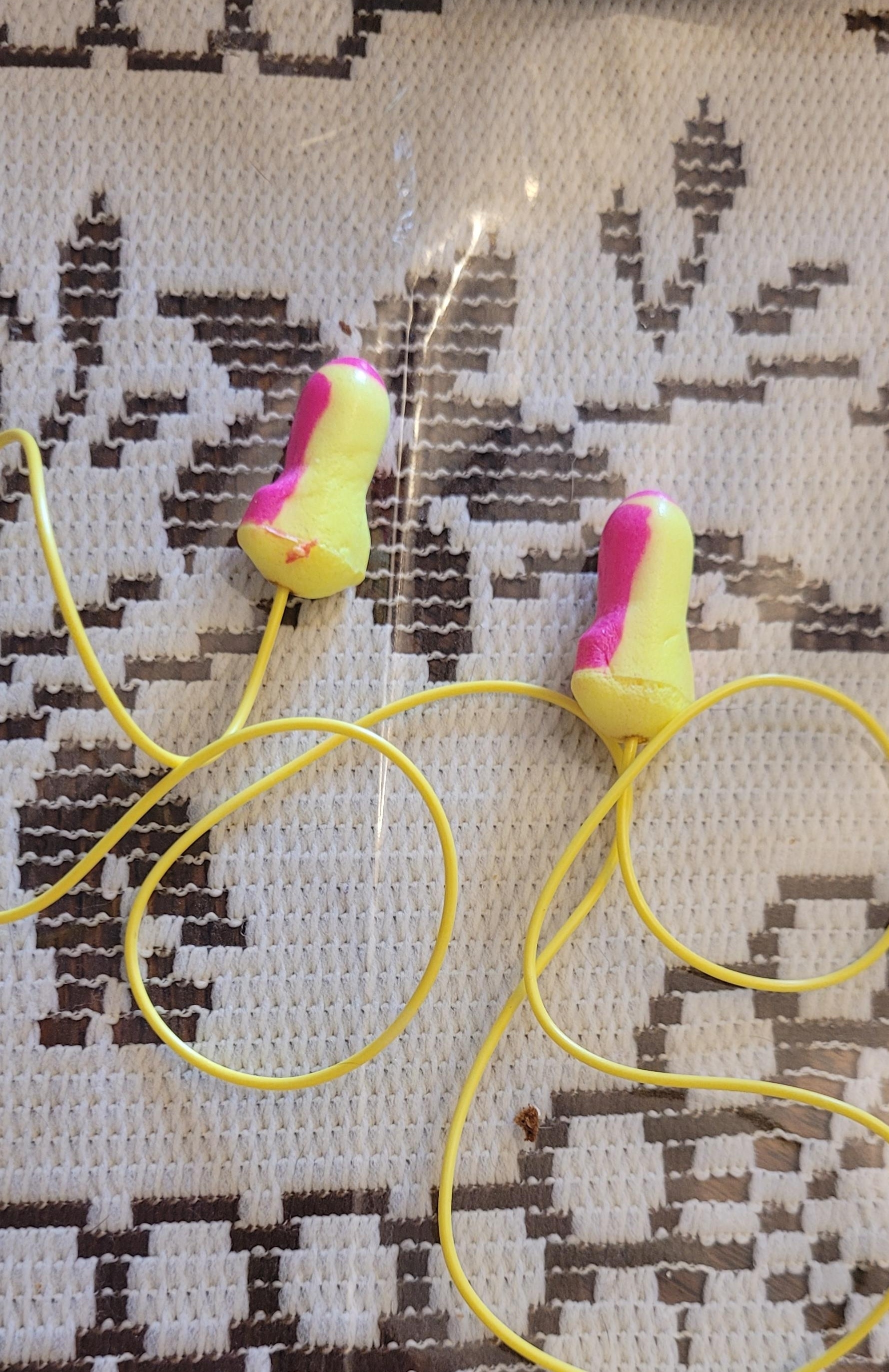 Pink-and-yellow earplugs connected with a yellow rope