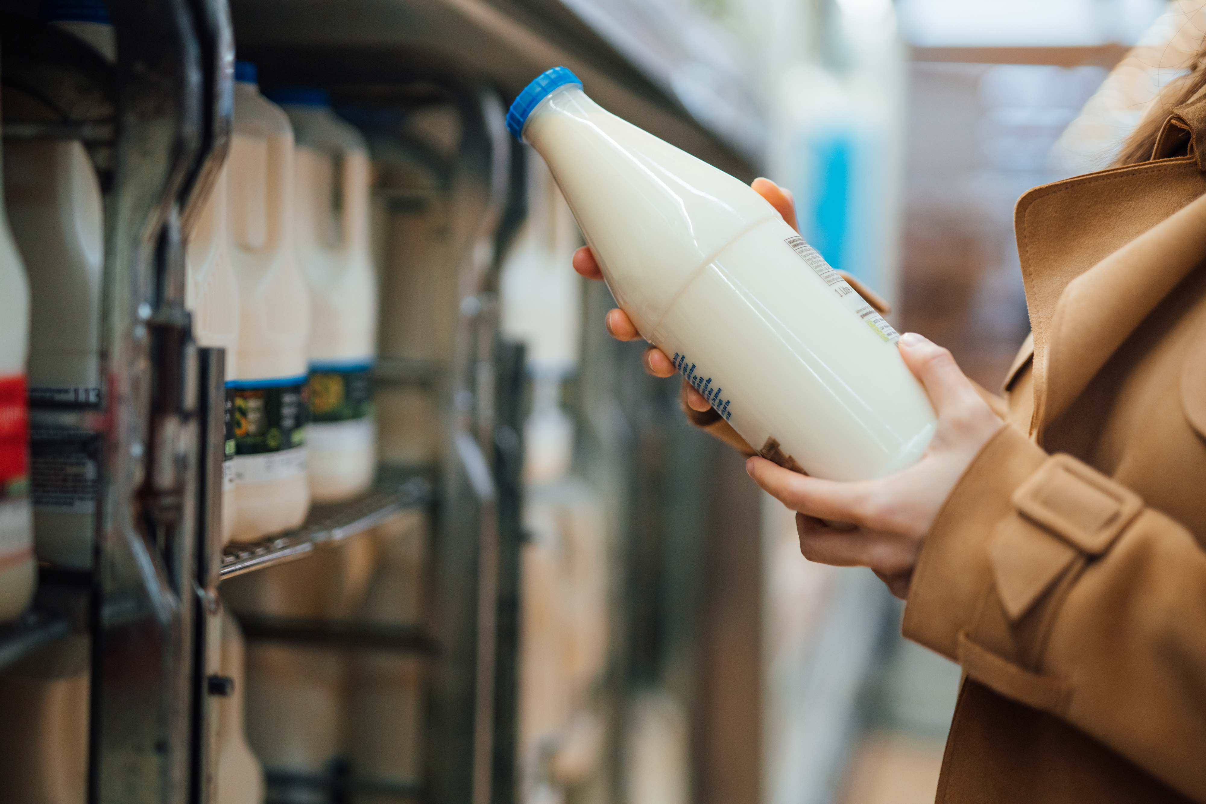 Close up shot of woman holding a bottle of organic unsweetened almond milk in supermarket