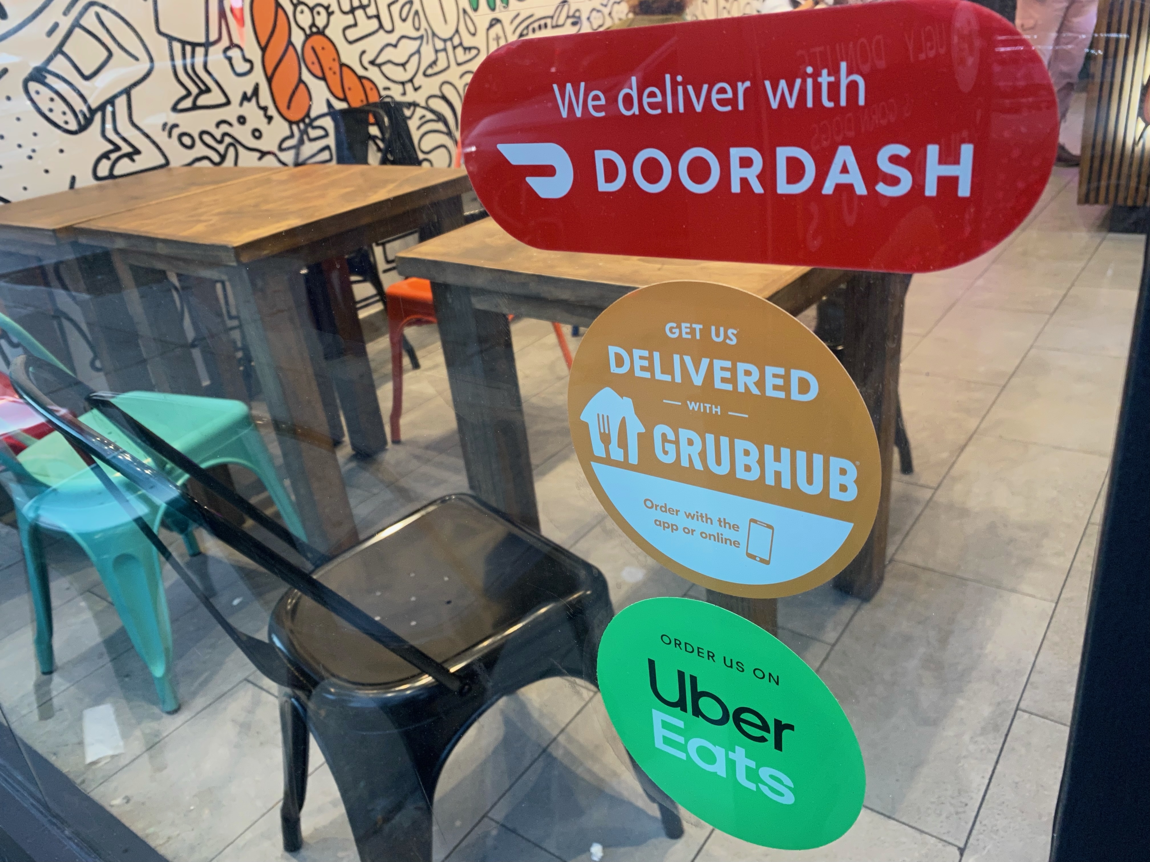 We Deliver, Doordash, Grubhub and Uber Eats signs on restaurant door