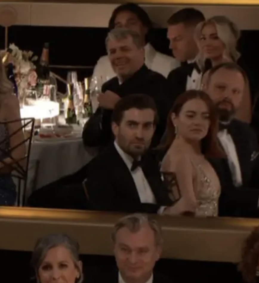 Emma looking sideways behind Christopher Nolan