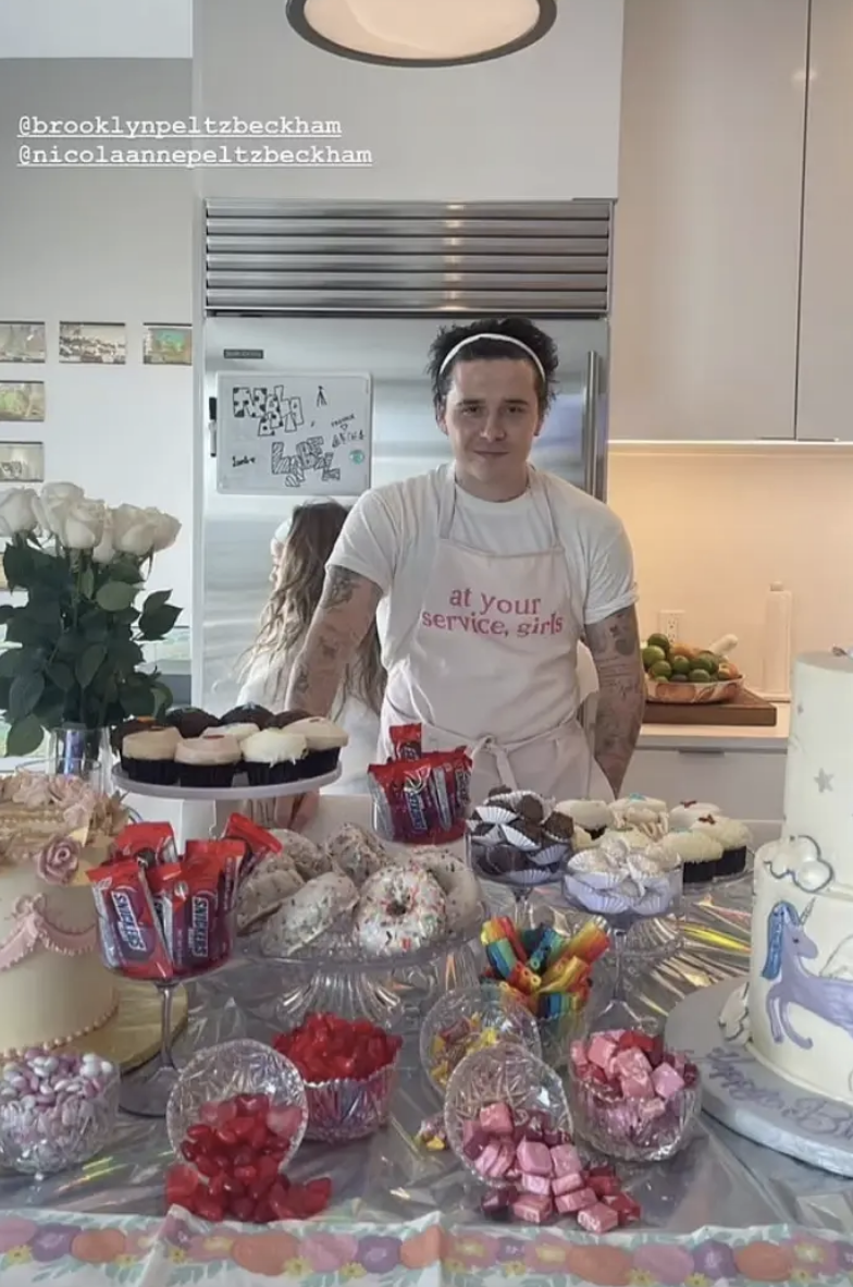 Brooklyn wearing the apron in front of a table of treats