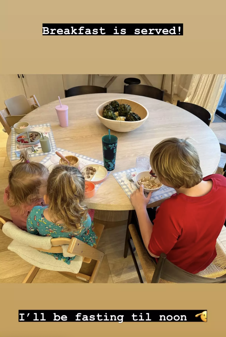 the kid&#x27;s have their backs to the camera as they sit at the kitchen table with breakfast in front of them