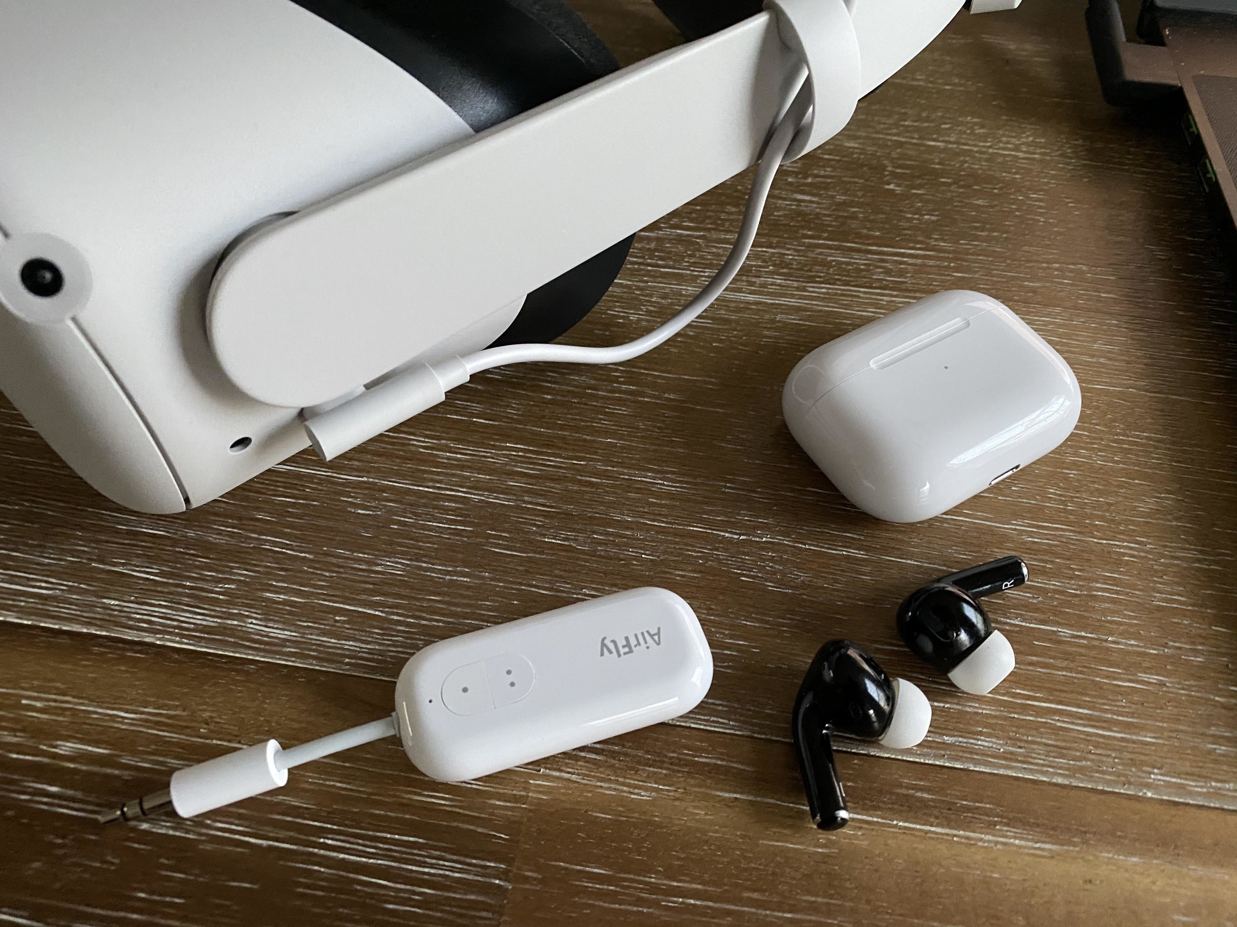 An AirFly device on a table next to wireless headphones