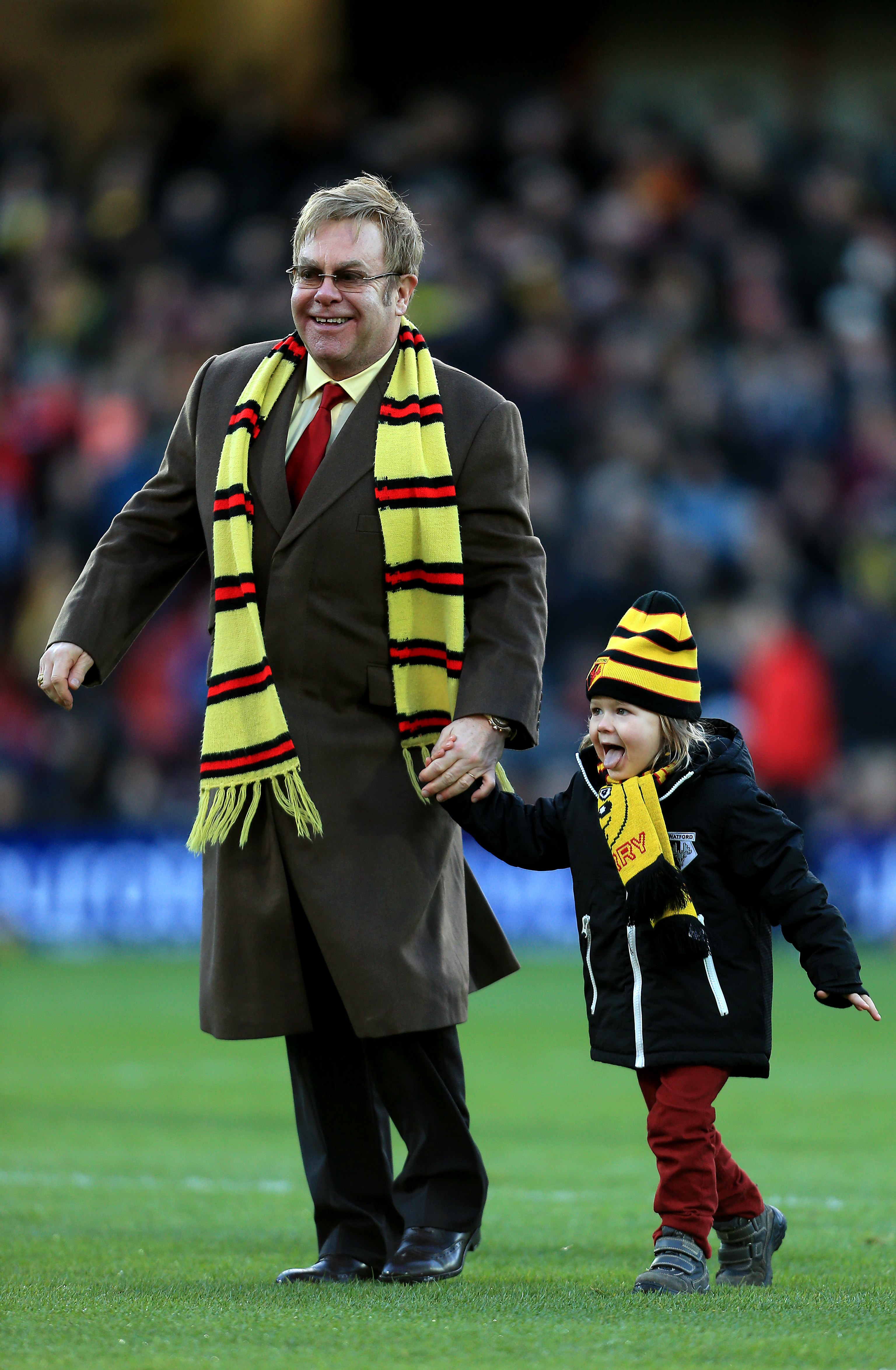 elton and his son walking on a soccer field