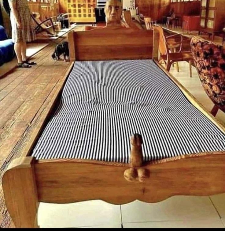 A wooden bed frame with a penis on it