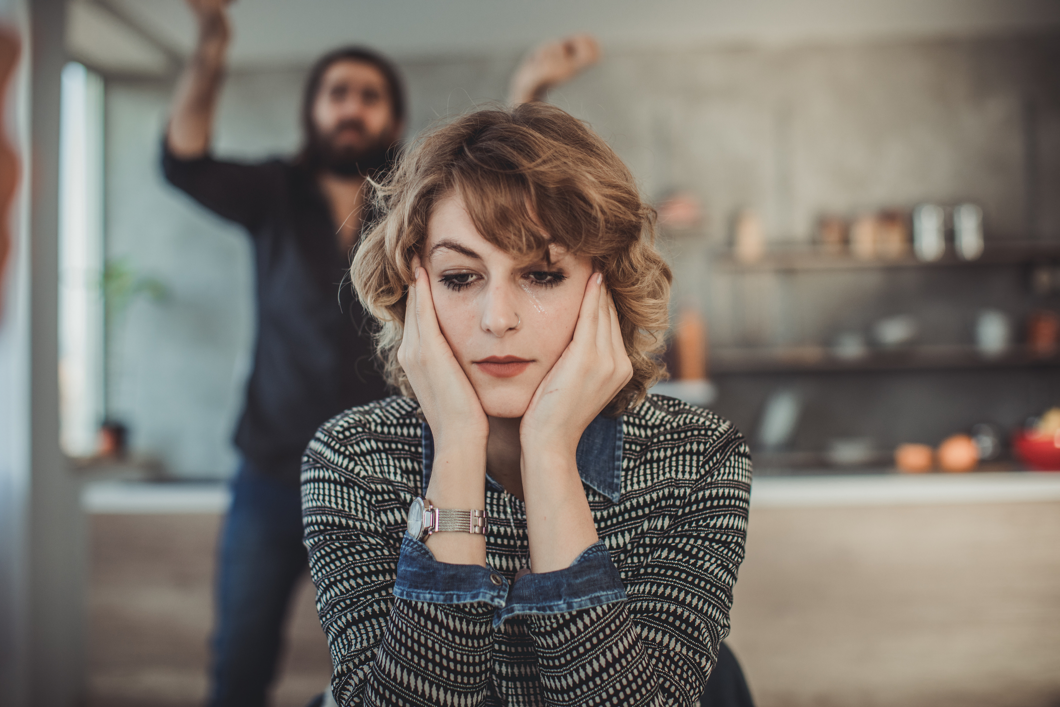 woman sitting and looking annoyed as a man yells behind her