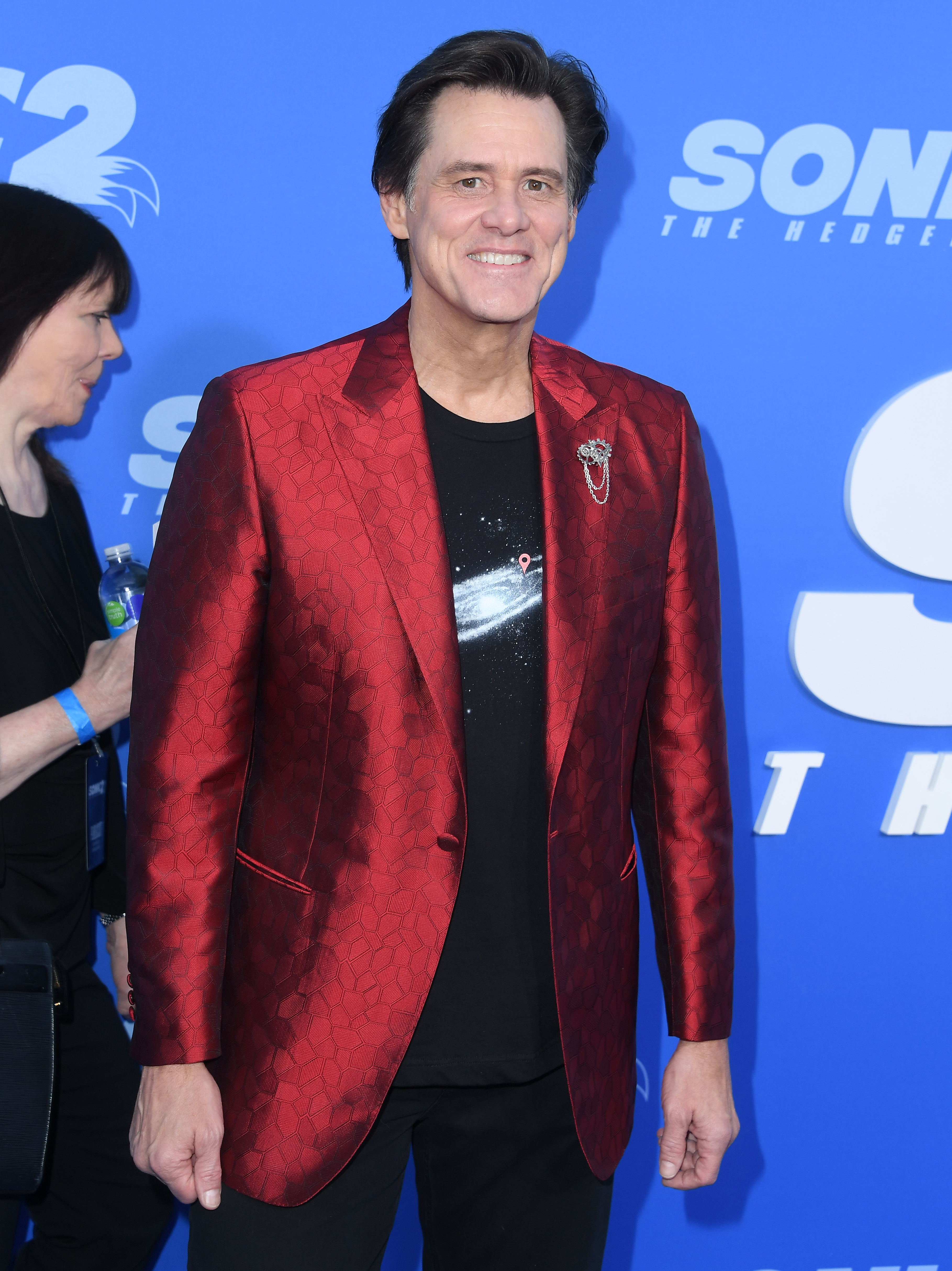 Close-up of Jim smiling in a shiny suit jacket at a media event