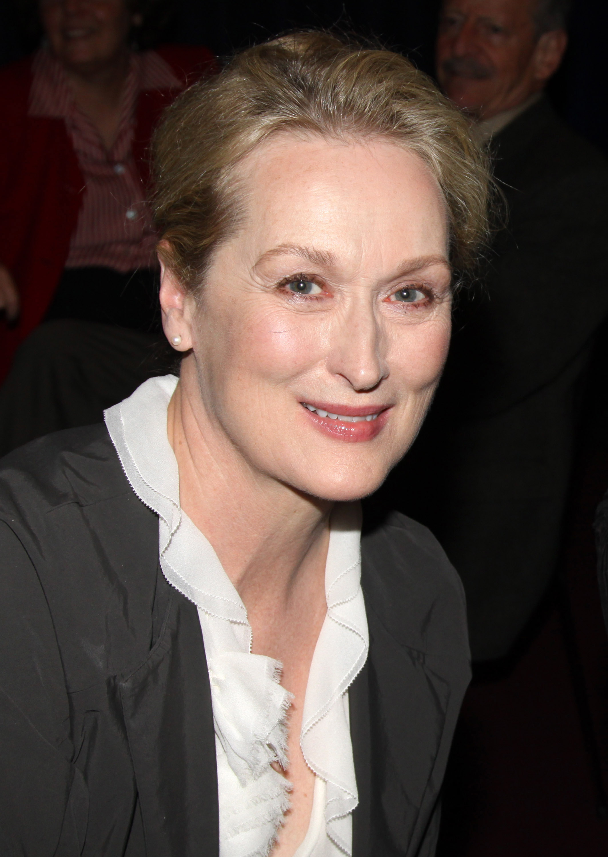 Close-up of Meryl smiling in a frilly blouse and jacket