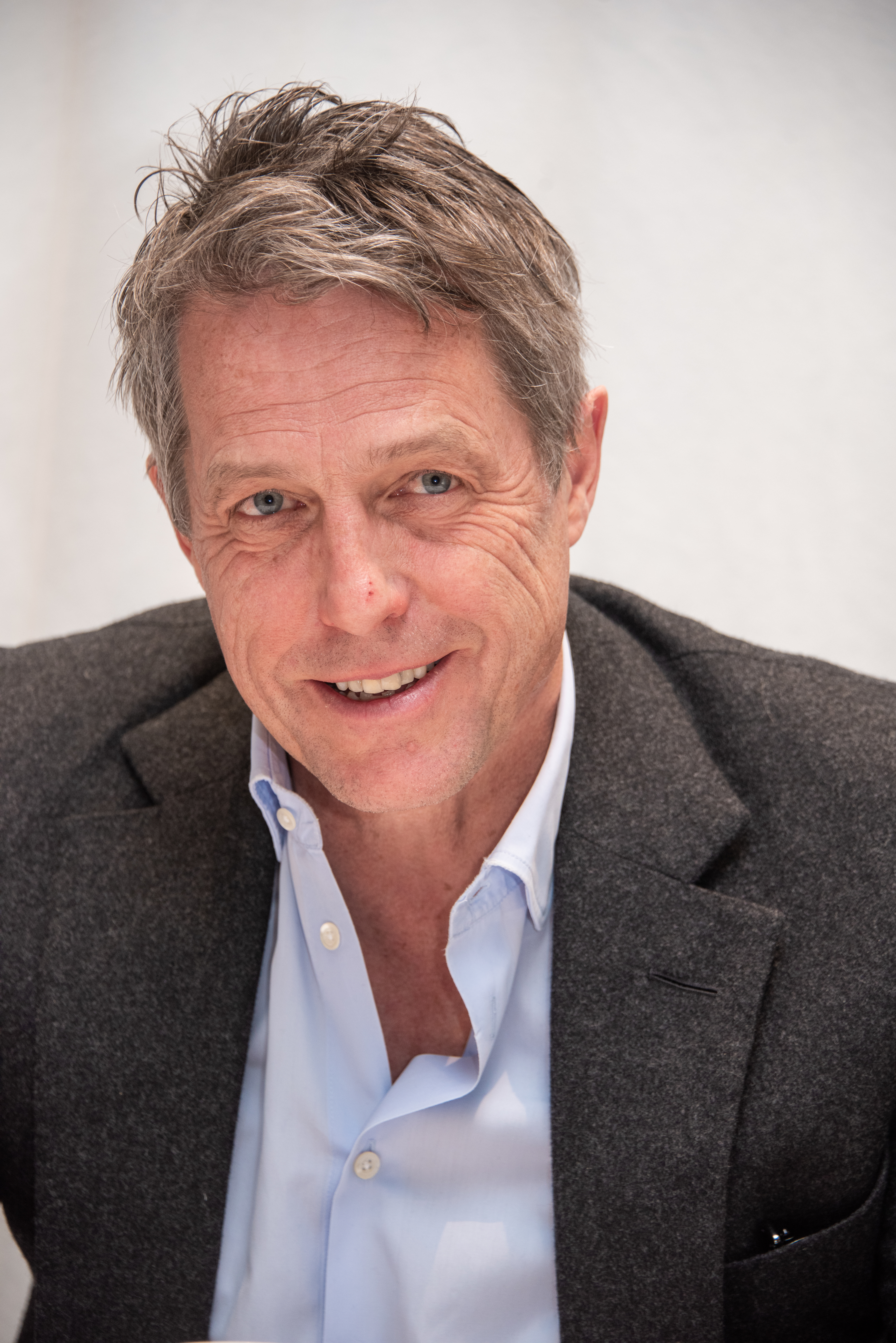 Close-up of Hugh smiling in a shirt and jacket