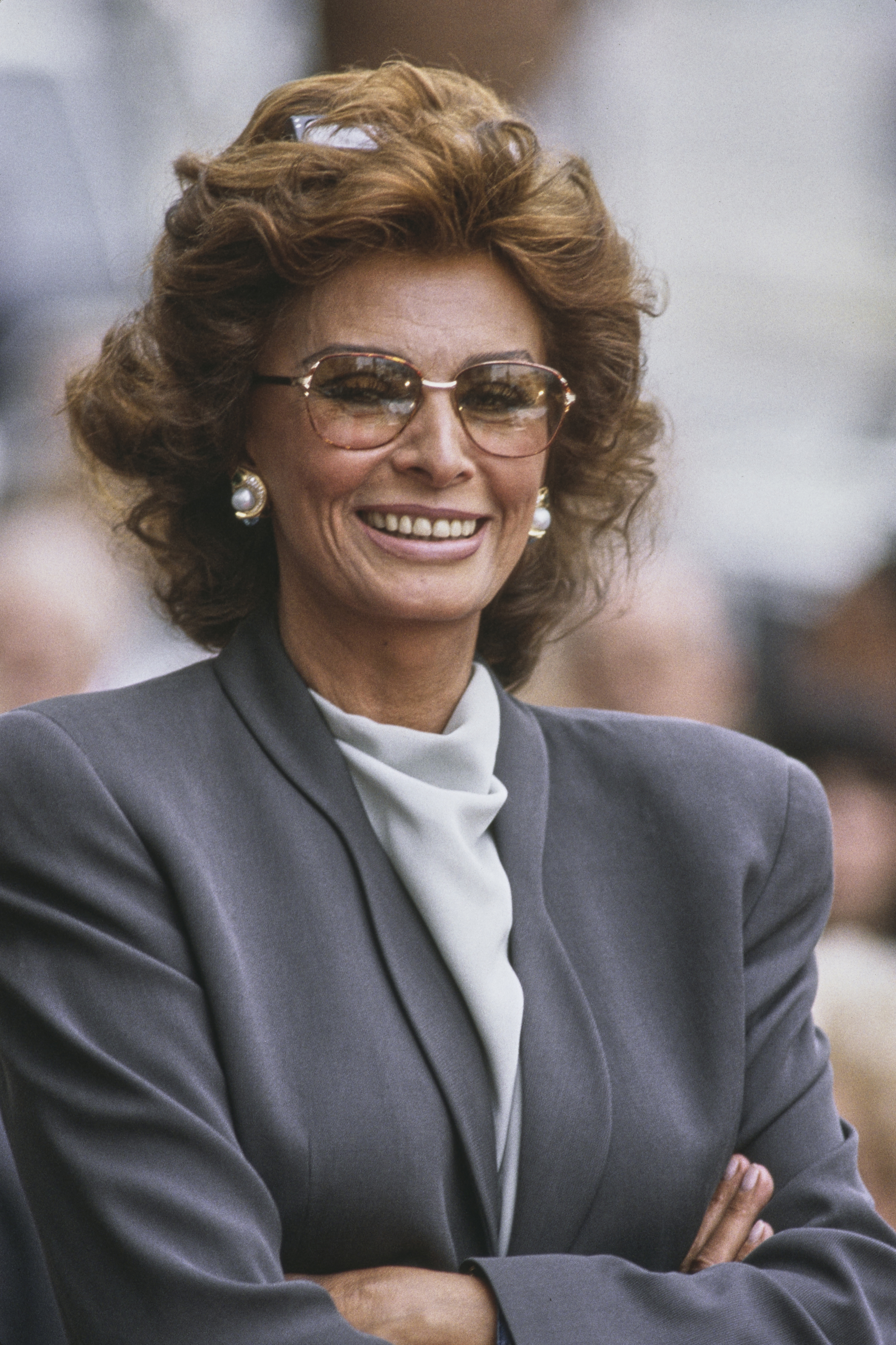 Close-up of Sophia smiling in a blouse and jacket and her arms crossed