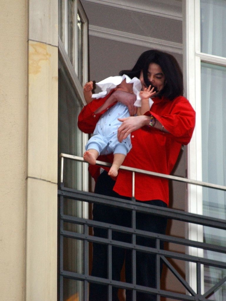 him holding his baby over the balcony