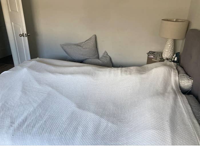 a person completely covered with a blanket in bed
