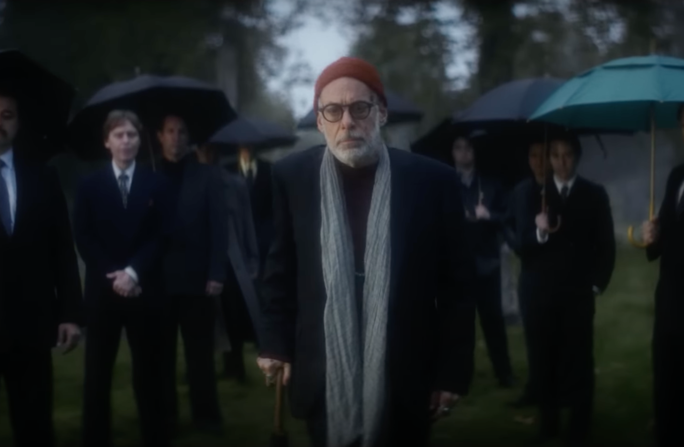 A man walks with a cane at a funeral.