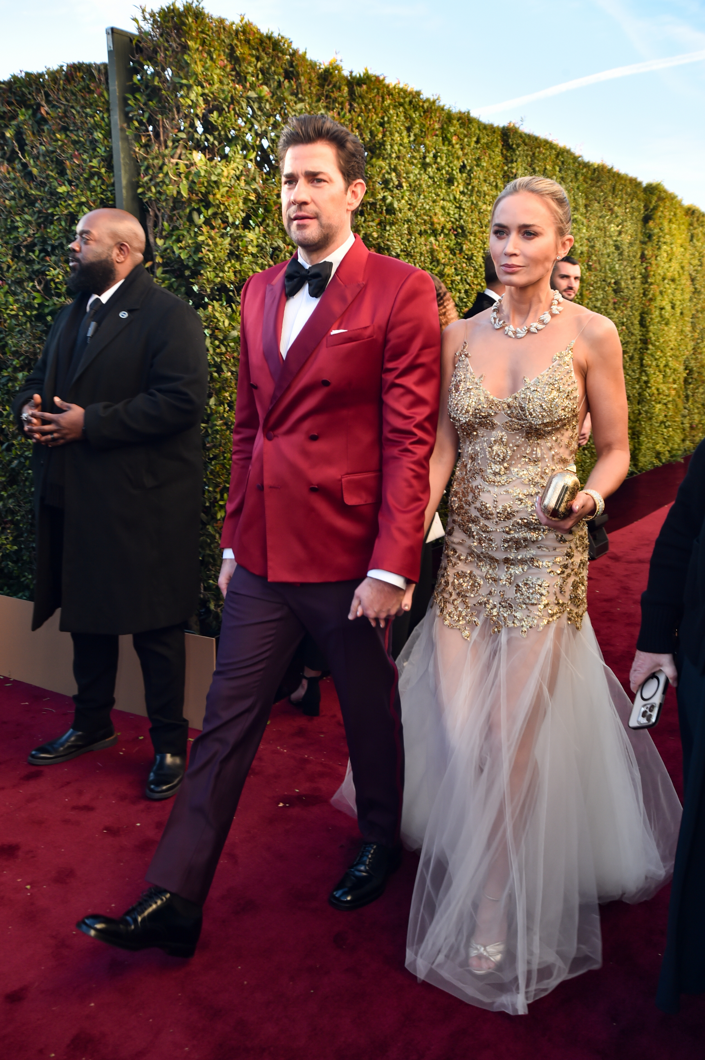 john and emily holding hands as they walk the red carpet