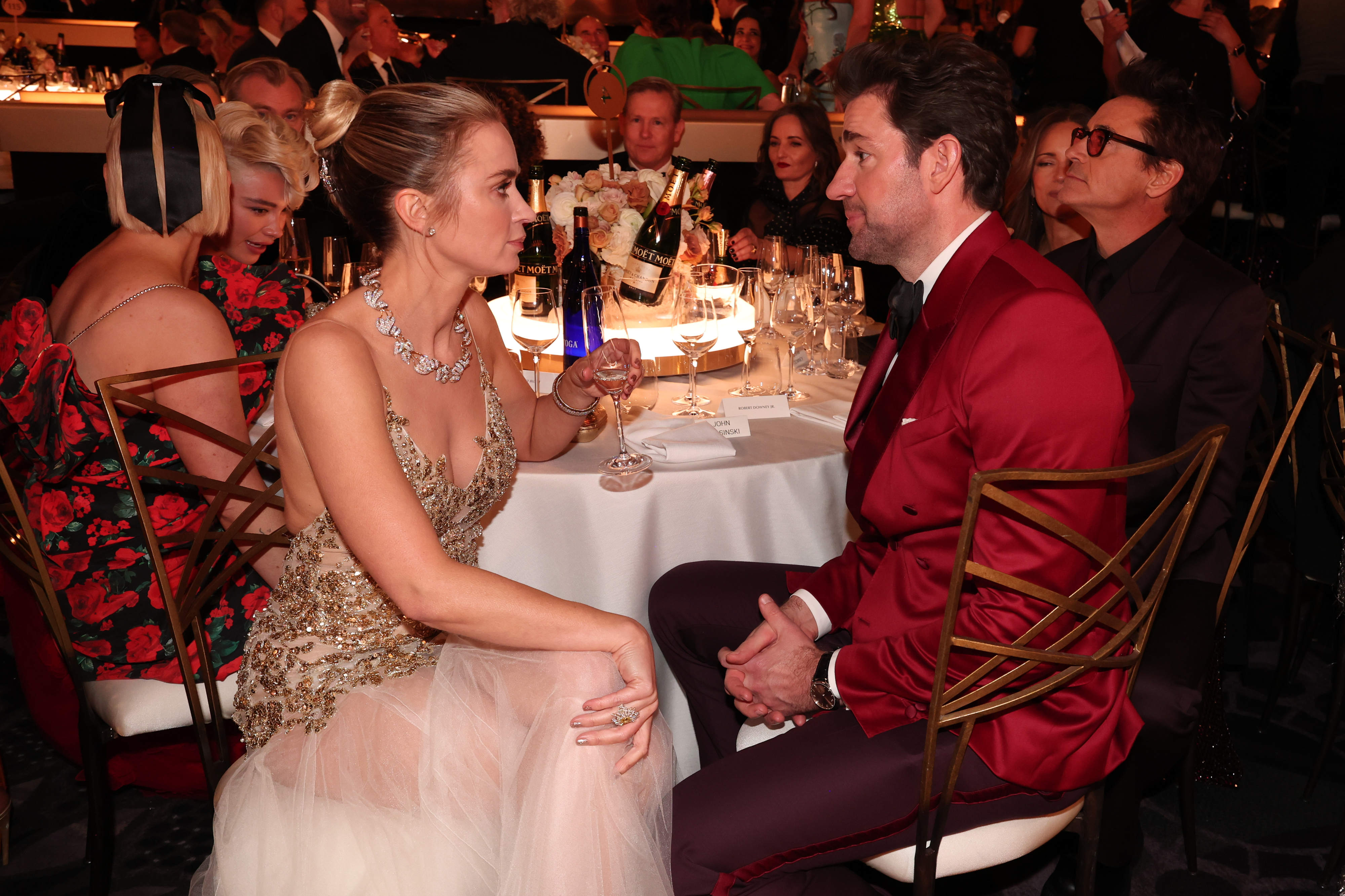 John and Emily looking at each other as they sit at a table during an awards show