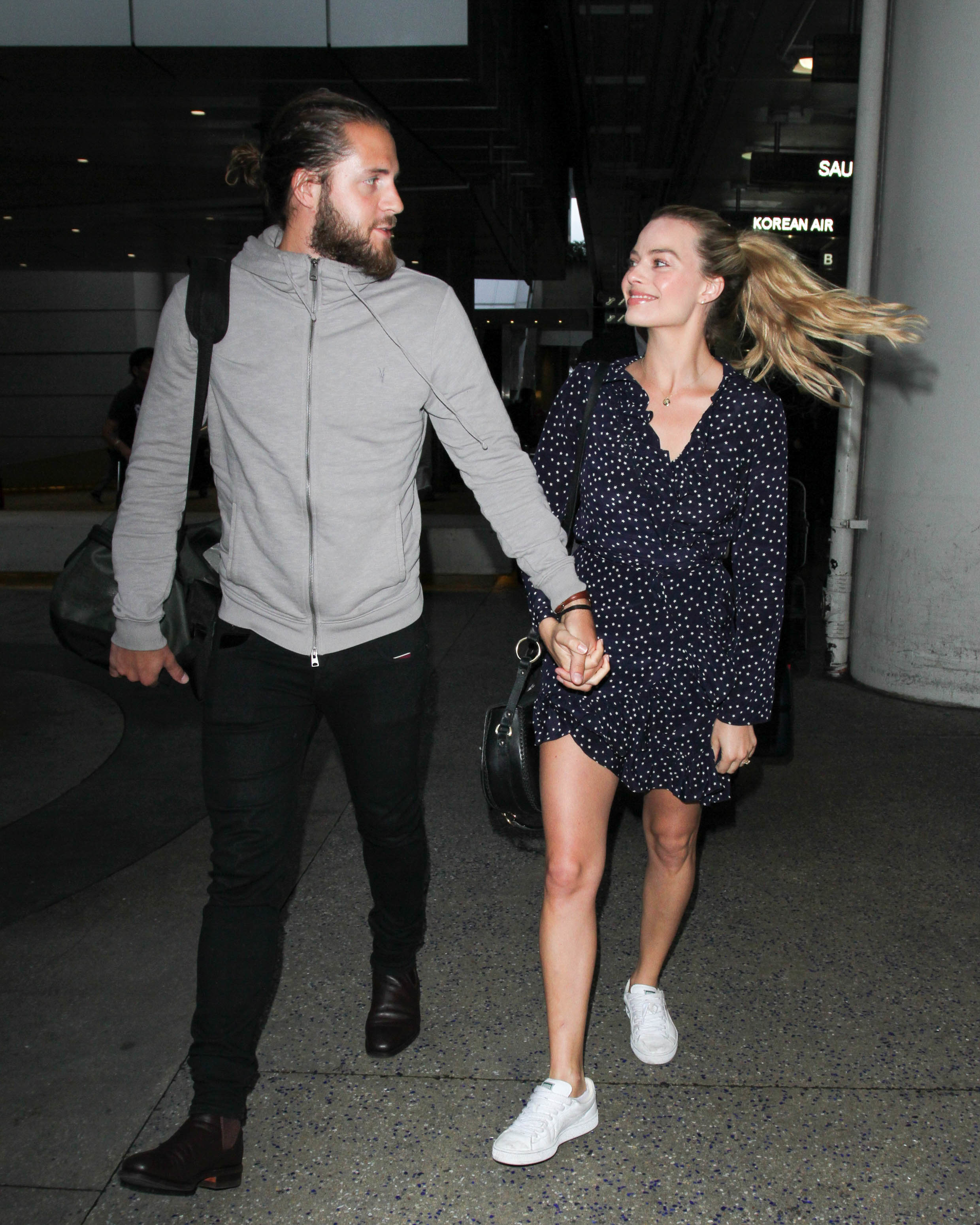 Tom Ackerley and Margot Robbie walking while holding hands