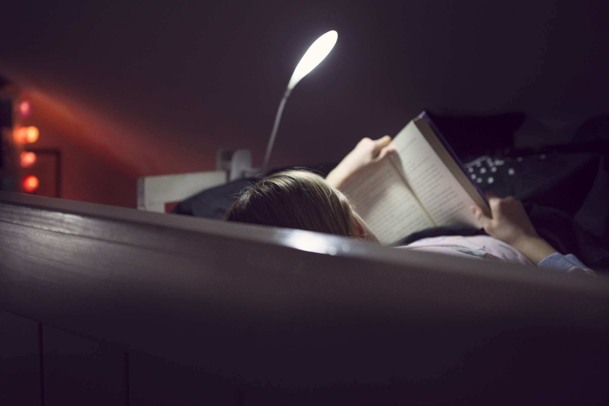 person reading in bed with a reading light