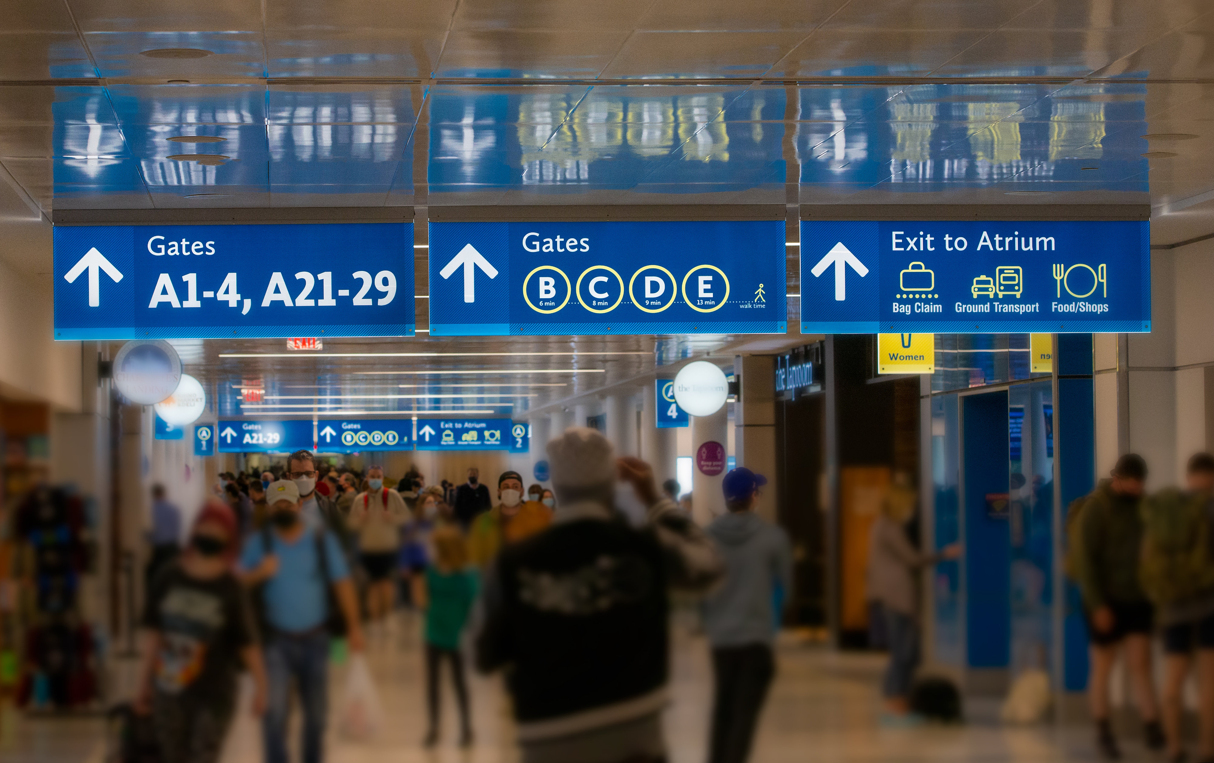 Airport Terminal signs with rushing commuters