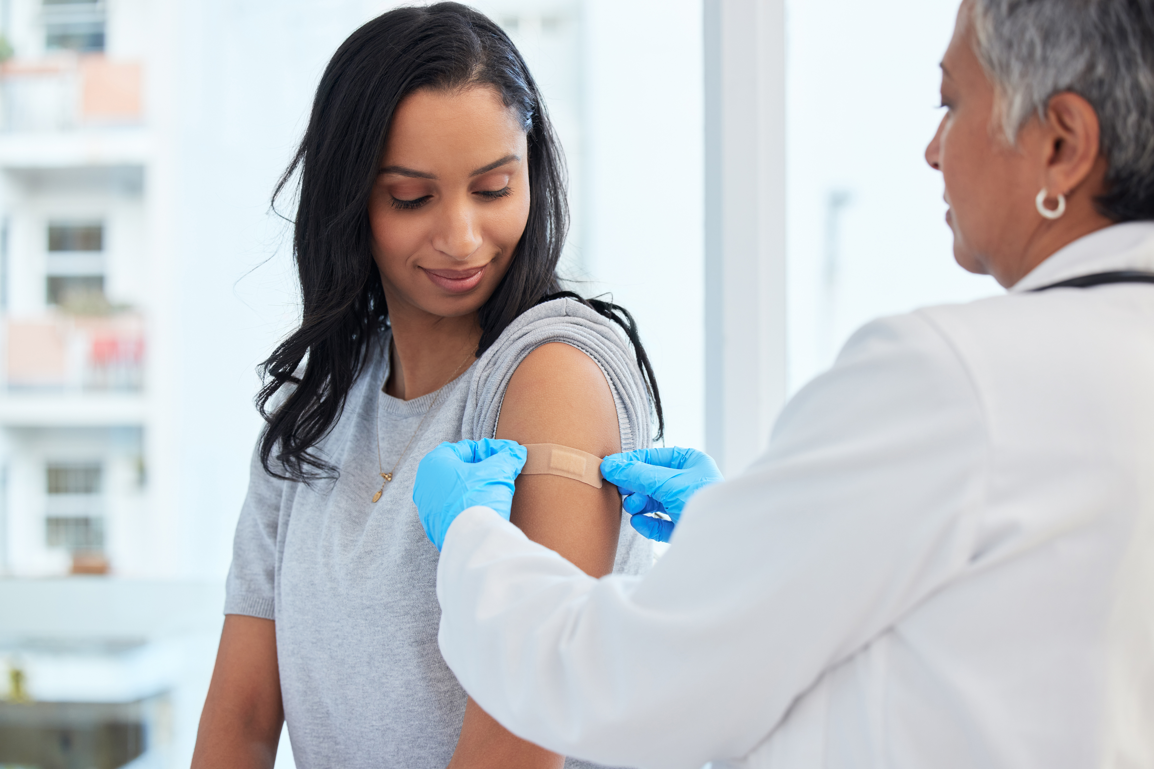 person getting a bandage over a vaccine in their upper arm