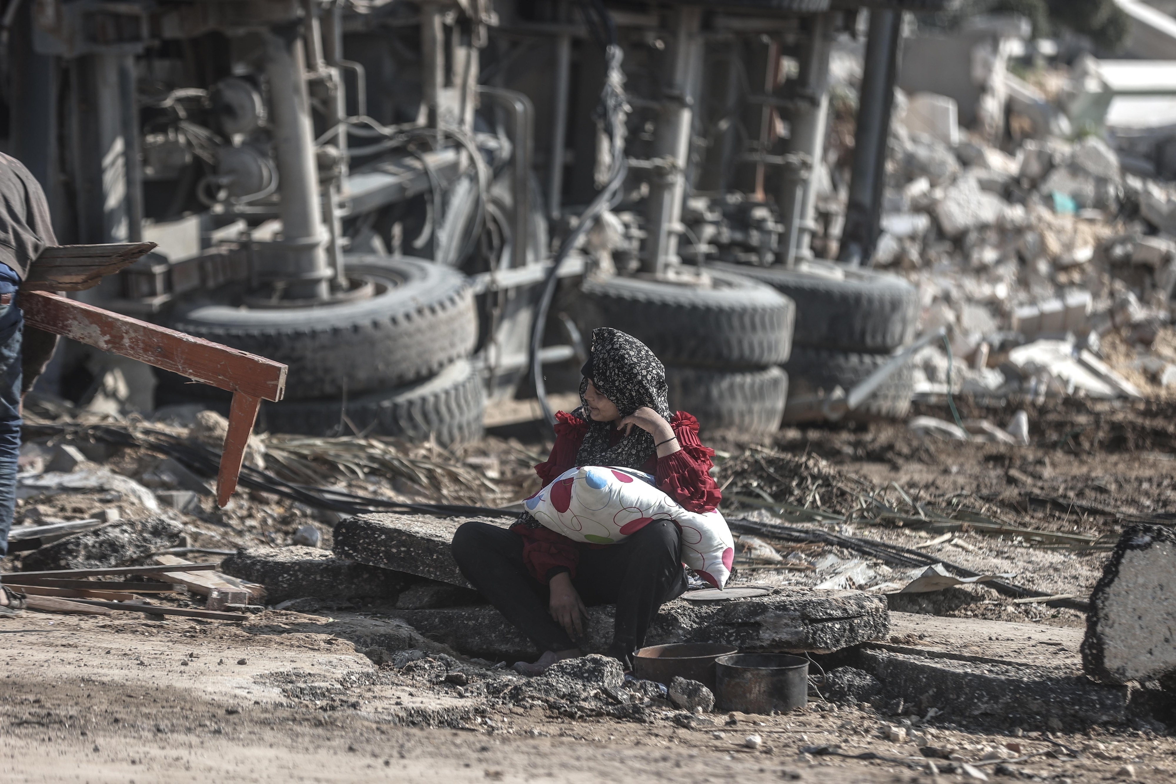 person sitting in the rubble holding a pillow