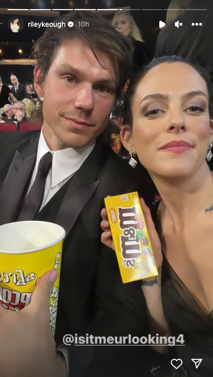 The couple is holding up m&amp;amp;ms and popcorn