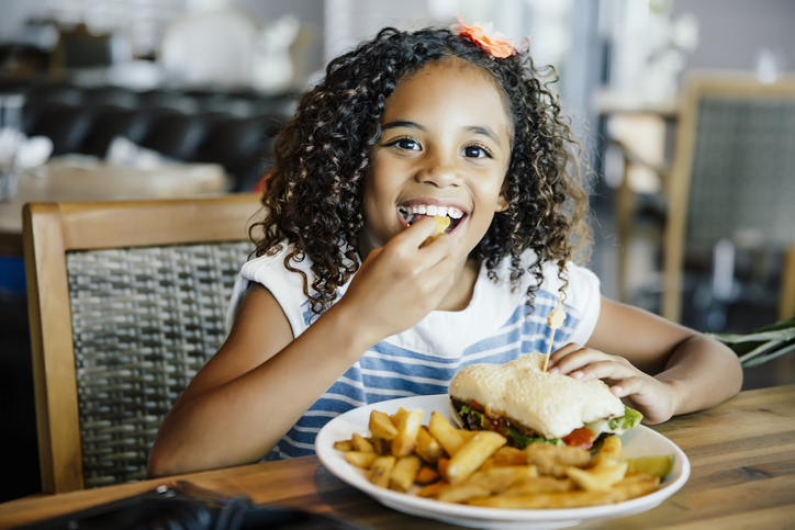 A little girl eating a burger and fries in a restaurant